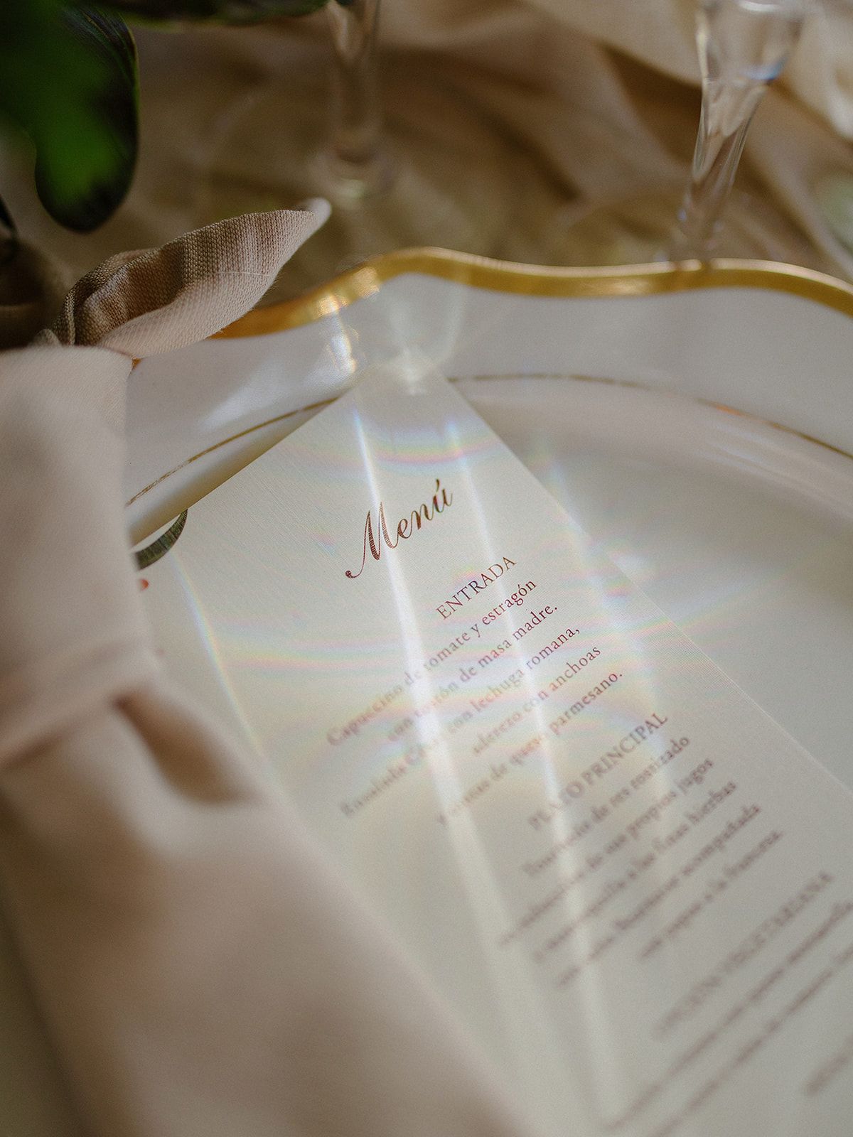Elegant wedding menu card with gold lettering on white linen tablecloth.