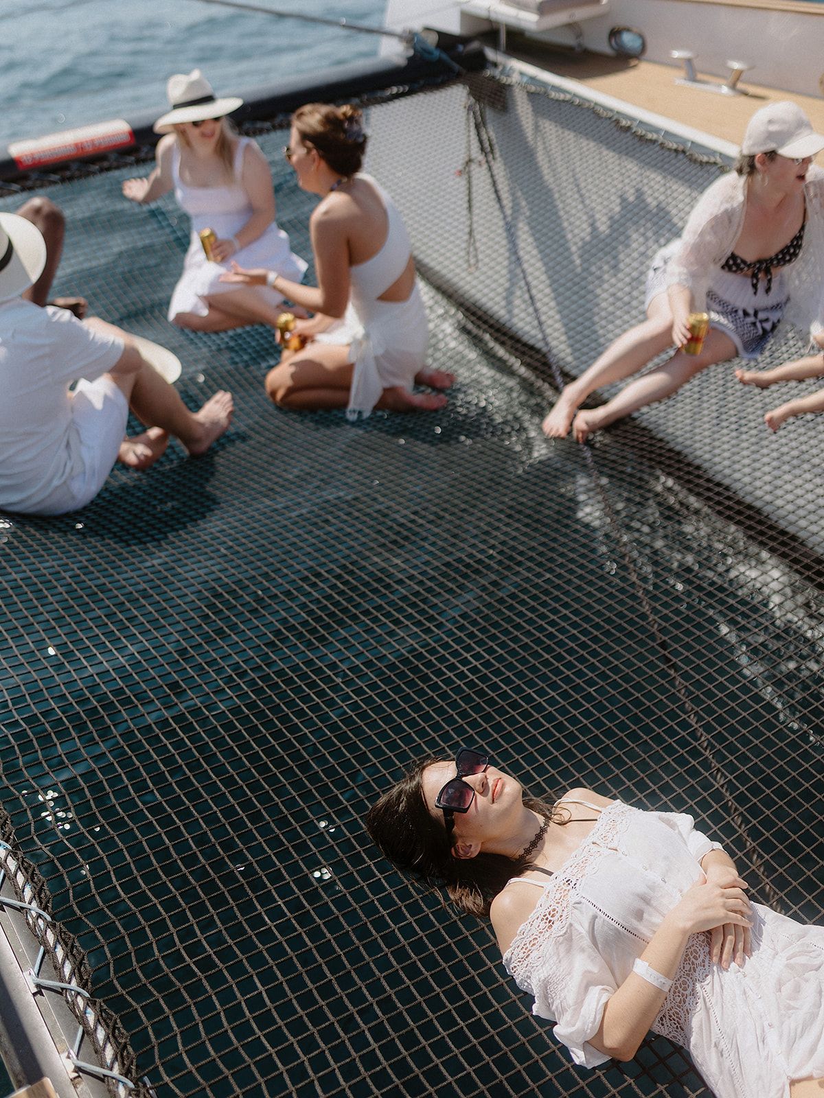 Wedding guests relaxing on a boat's mesh deck over the ocean.