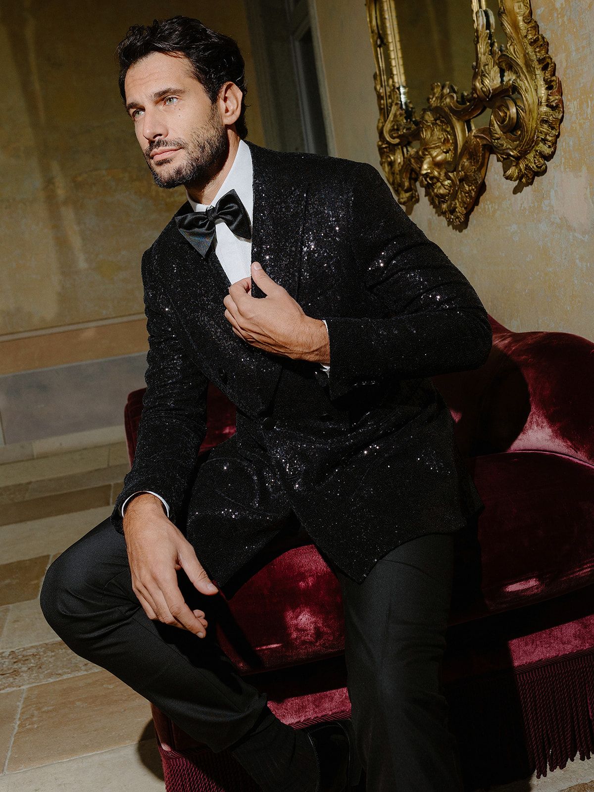 Sophisticated evening wear posed on luxurious red velvet furniture.