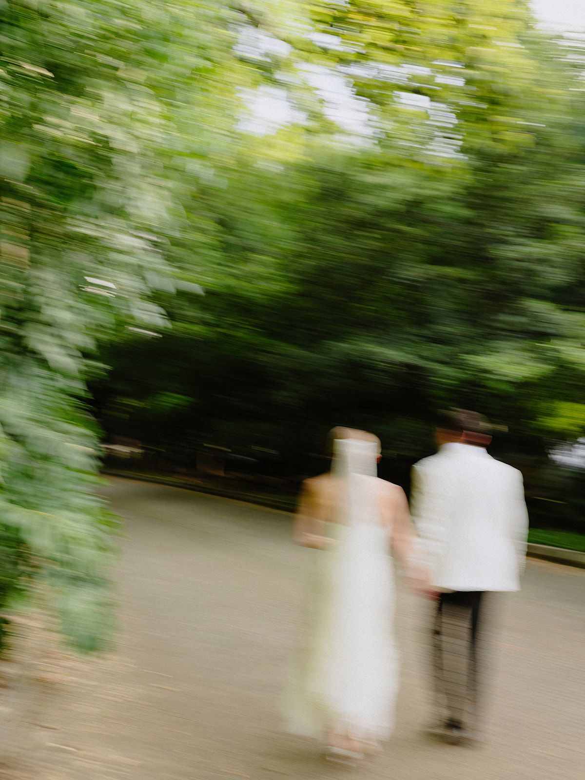 Artistic motion blur photo of couple walking through a garden path.