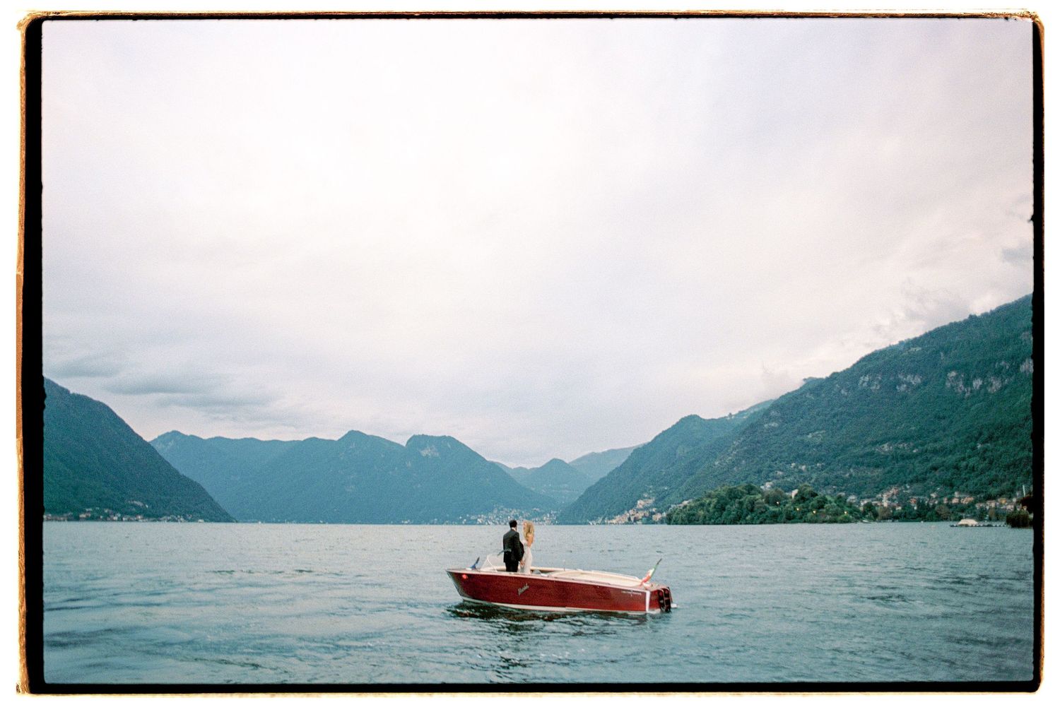 Wooden boat floating on a misty mountain lake surrounded by hills.
