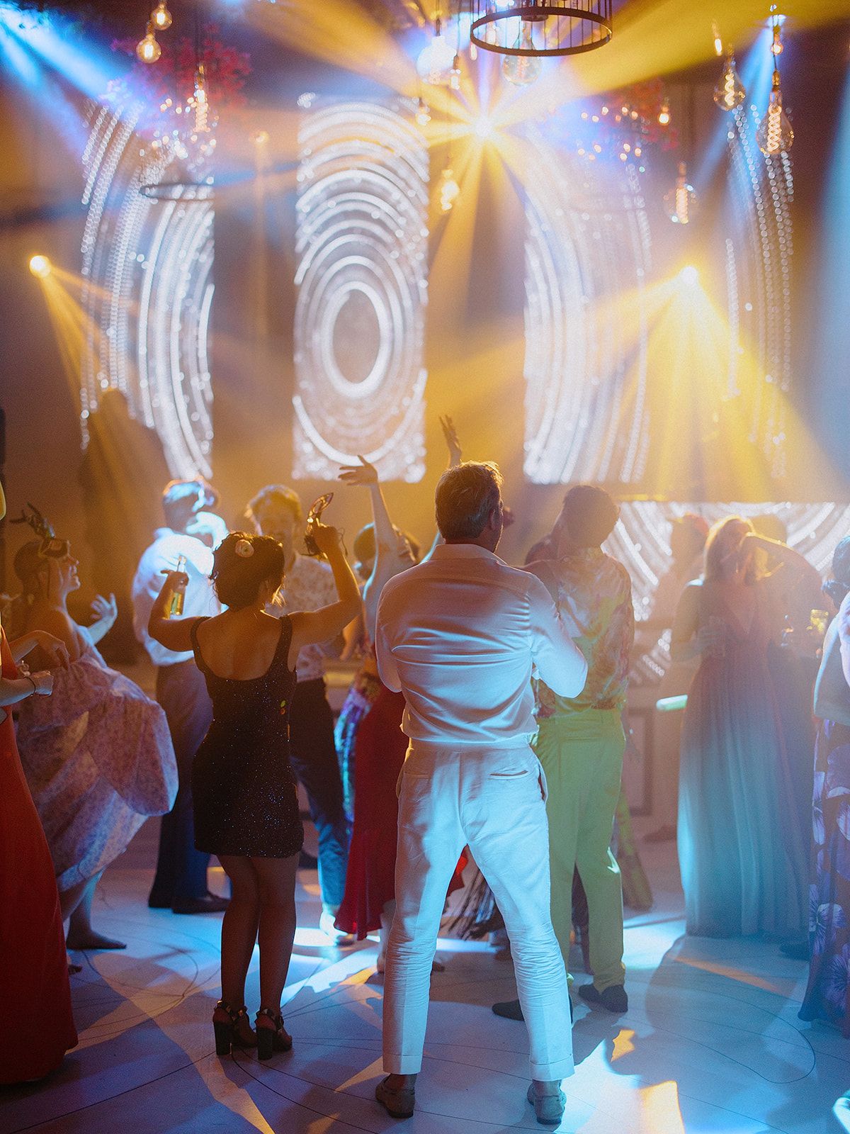 Dance party scene with colorful lighting effects and circular projections on the wall.