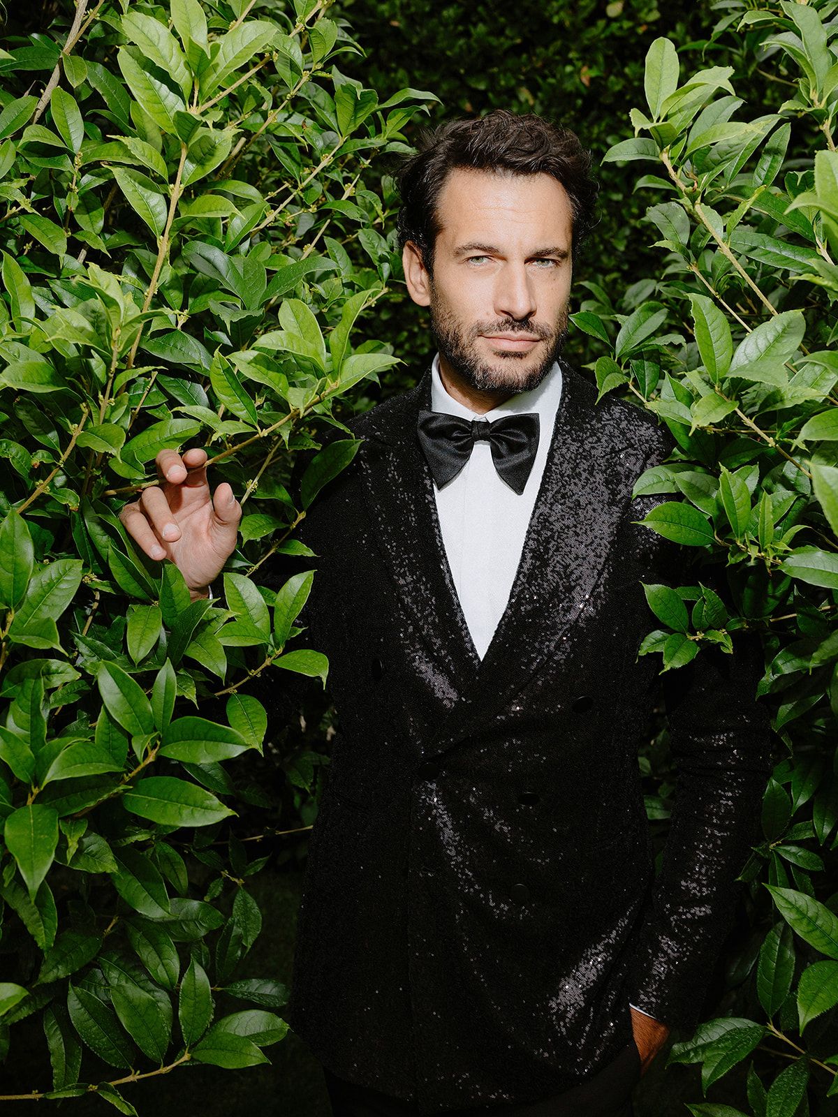 Formal black tie attire photographed against green garden foliage.