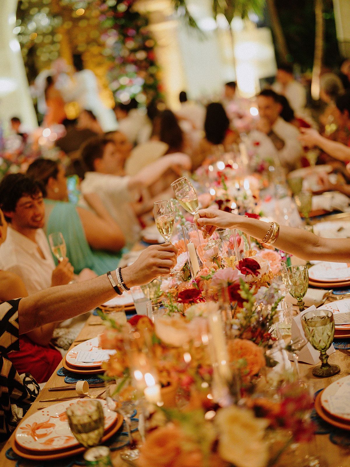 Wedding reception table decorated with pink floral centerpieces and glowing candlelight.