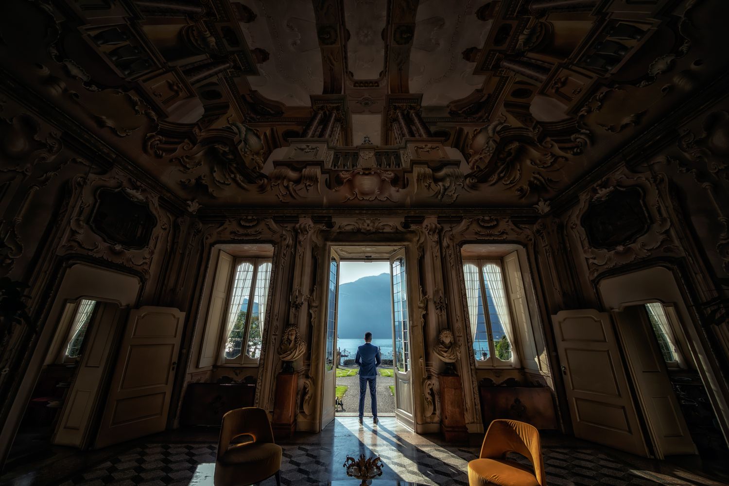 Silhouette in ornate palace room with dramatic lighting and mountain view through windows.