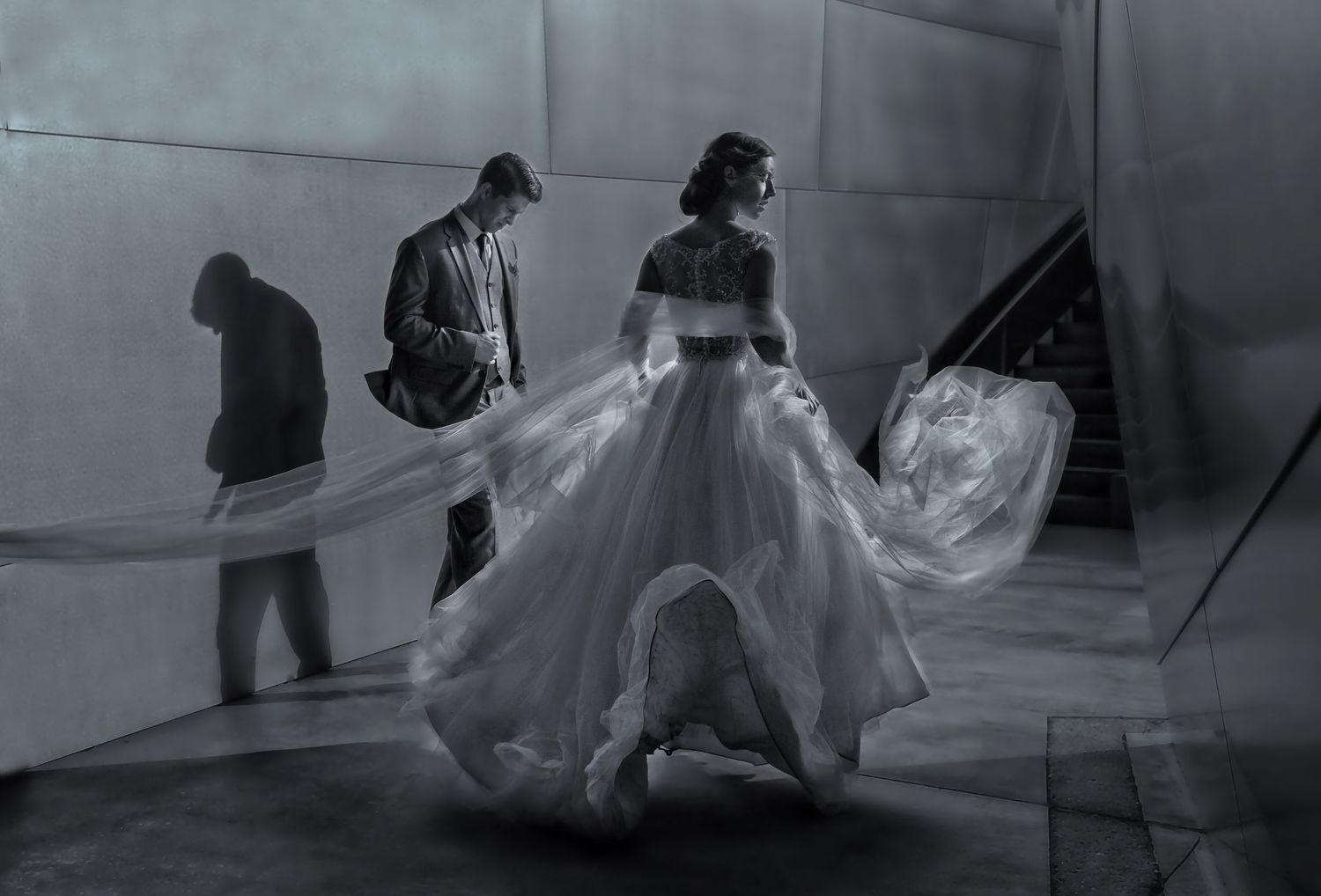 Dramatic black and white photo of a flowing wedding dress and veil in motion.