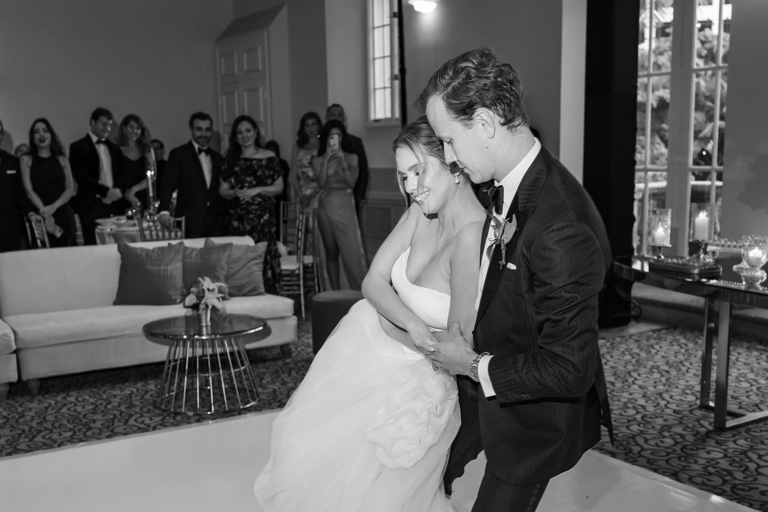 Black and white photo of bride and groom sharing their first dance at elegant wedding reception.