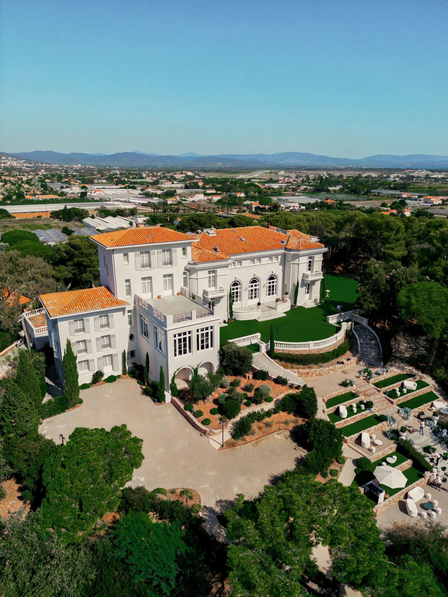 Aerial view of luxurious Mediterranean villa with orange tile roofs and manicured gardens.