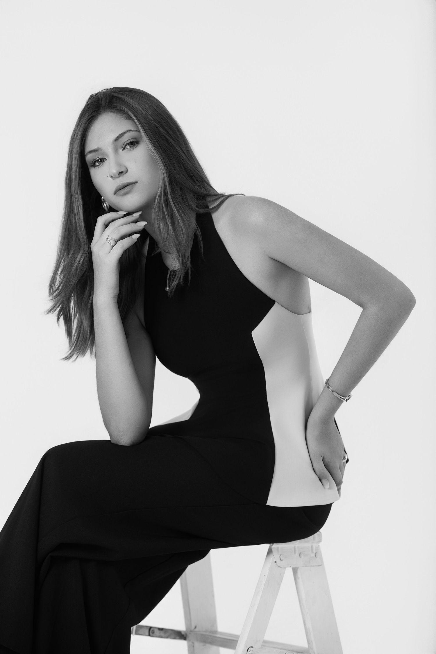 Artistic black and white portrait series showing modern fashion poses on white chair.