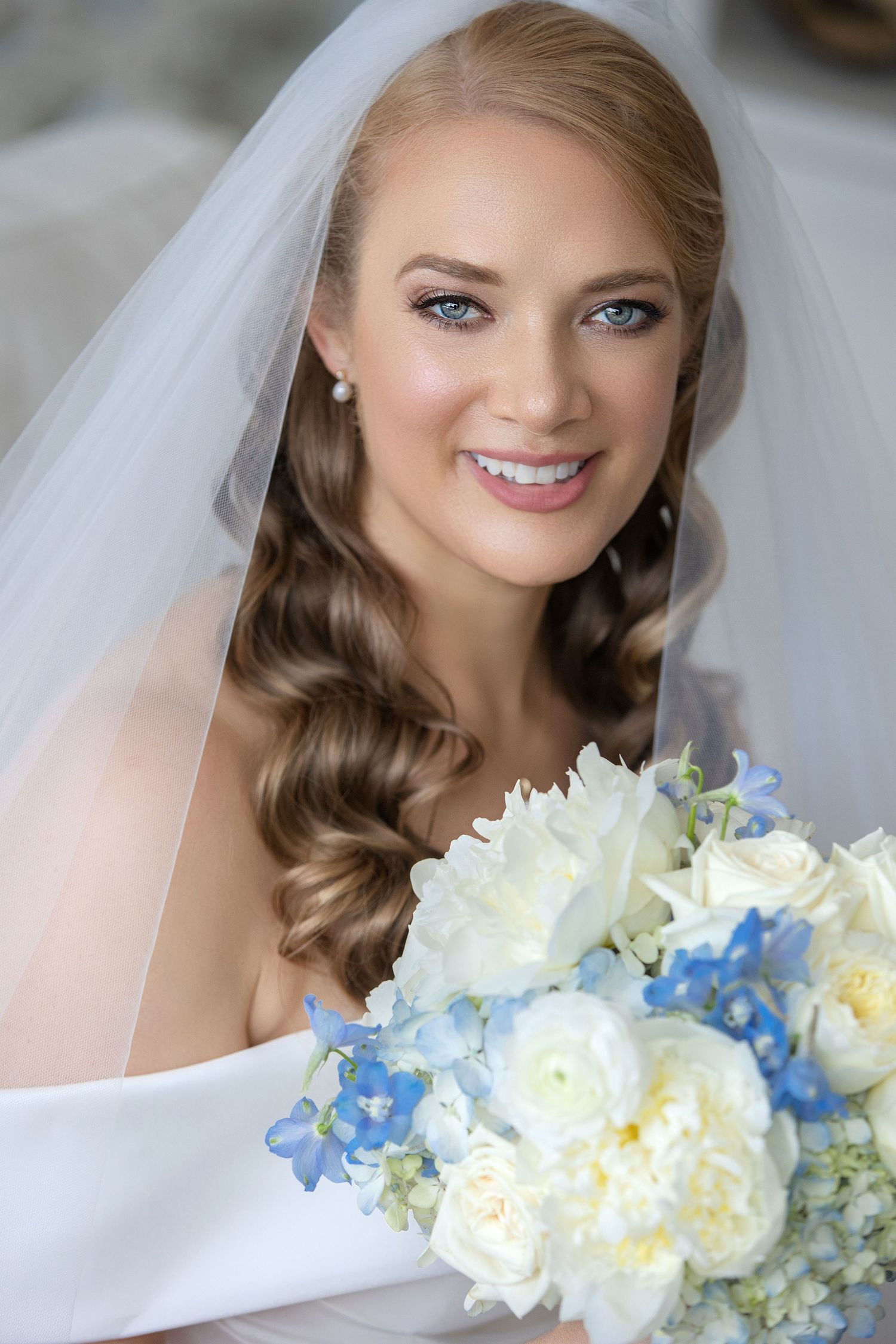 Elegant bridal portrait with white and blue floral bouquet.