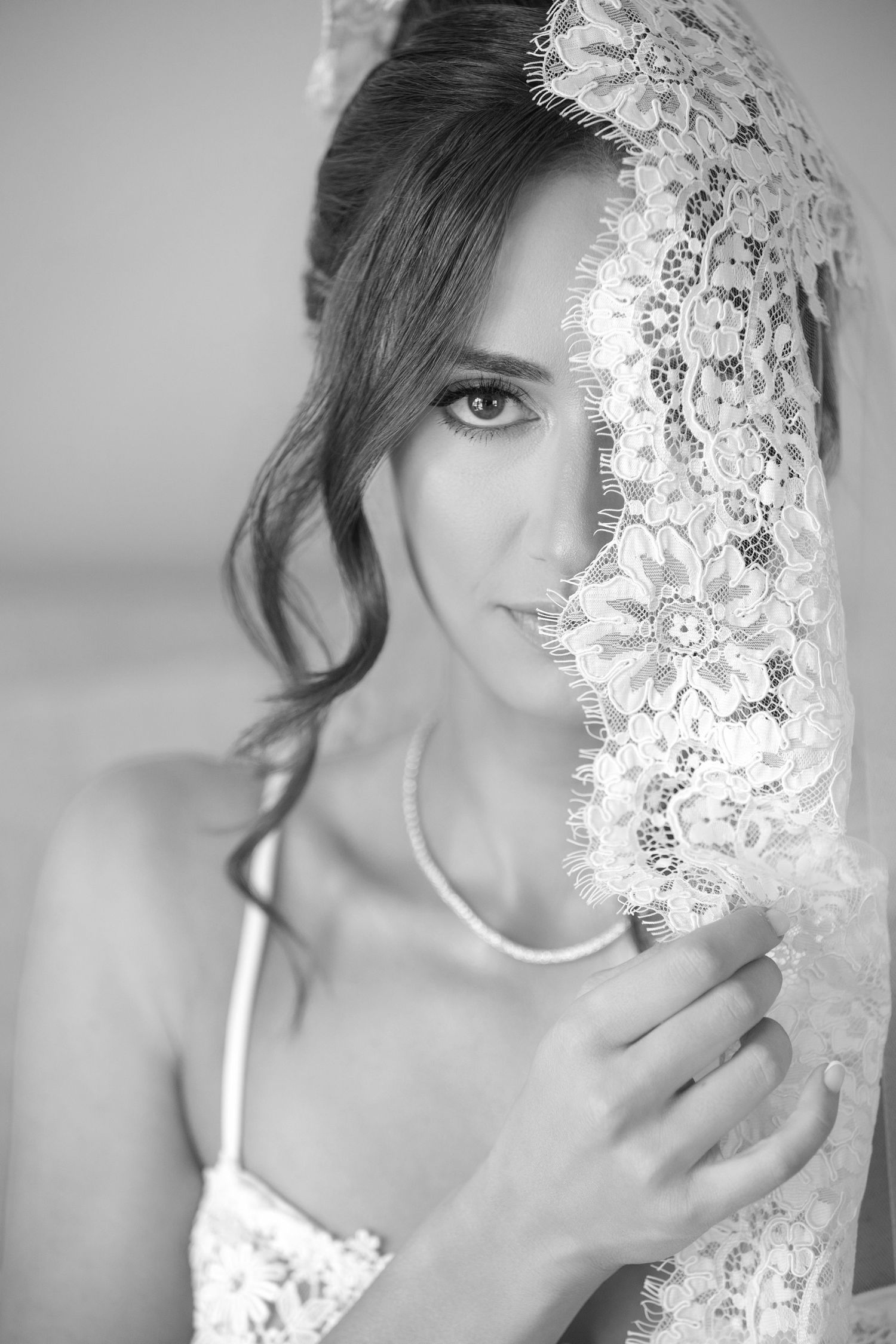A black and white portrait series showing a delicate lace veil against soft lighting and romantic styling.