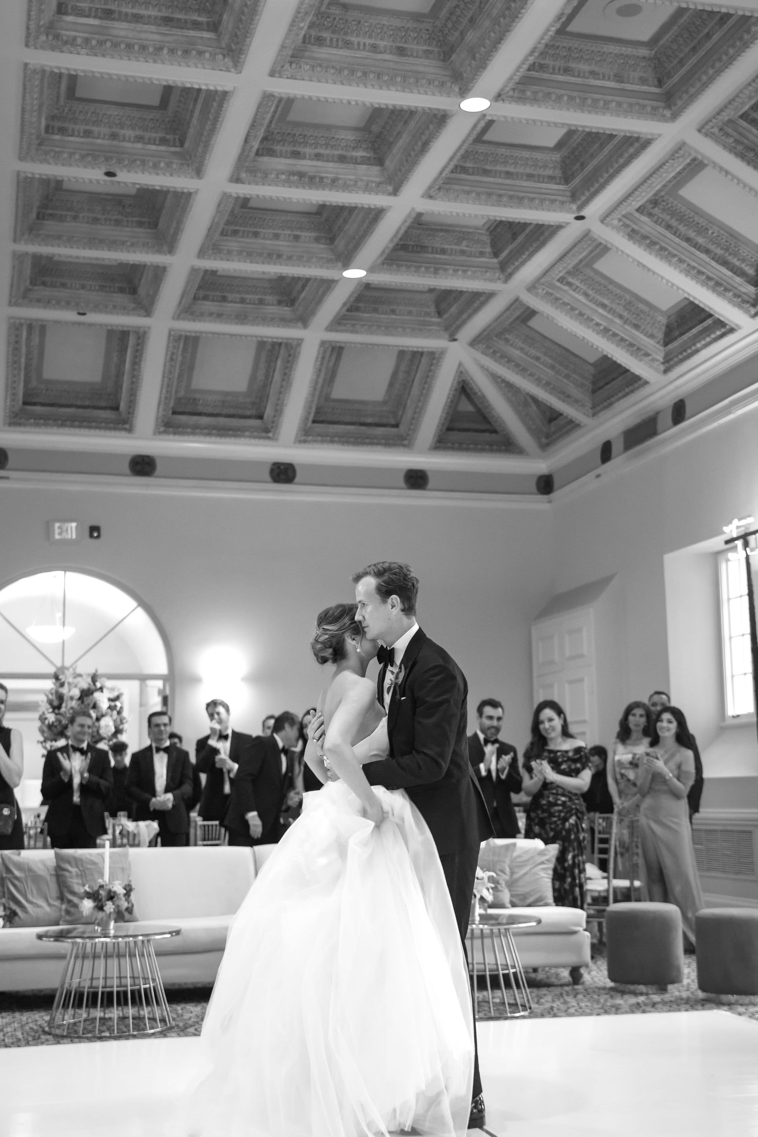 Black and white photo of a bride and groom sharing their first dance at an elegant wedding reception.