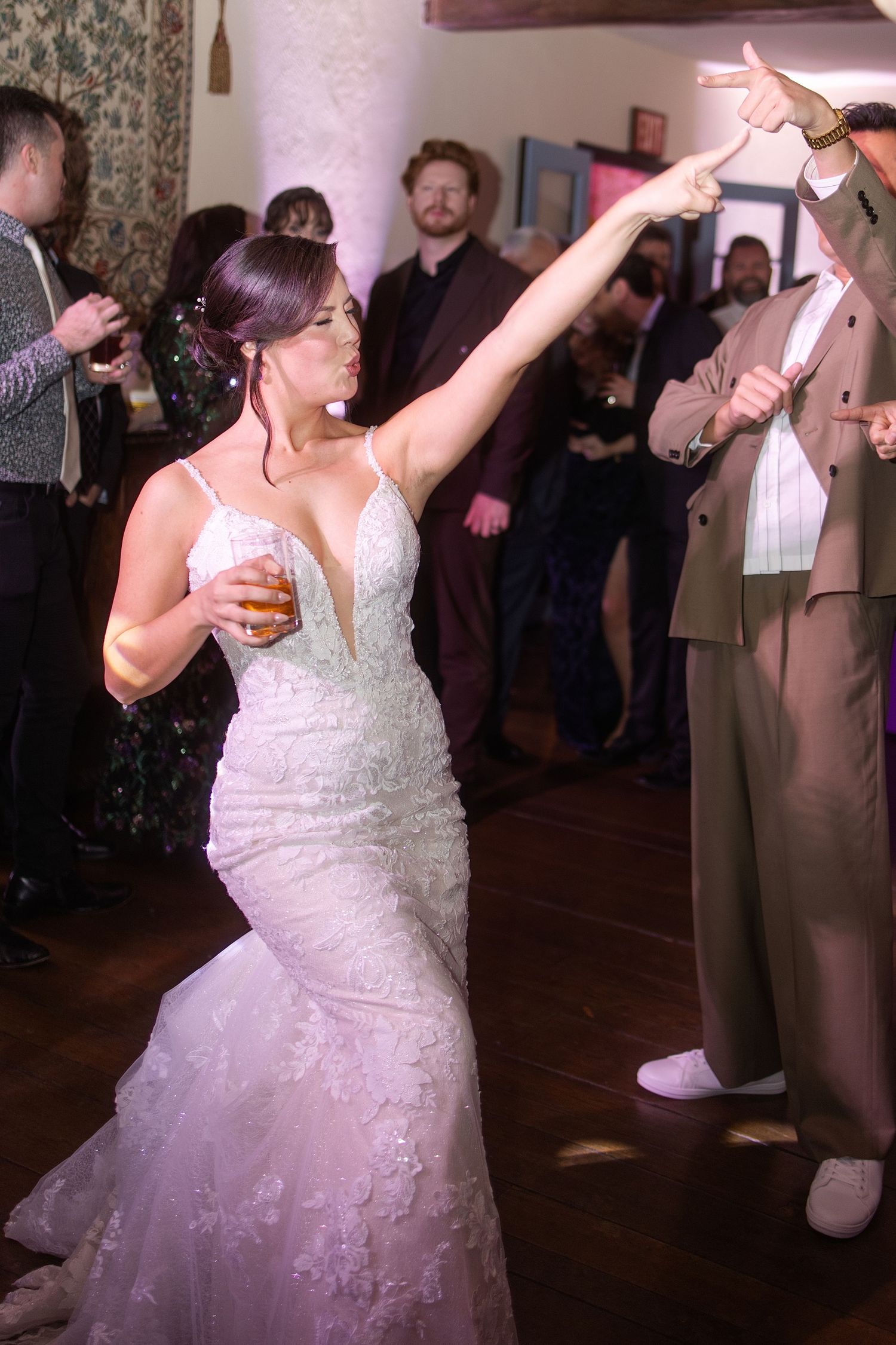A person in a white lace wedding dress twirls and dances on the dance floor during a wedding reception.
