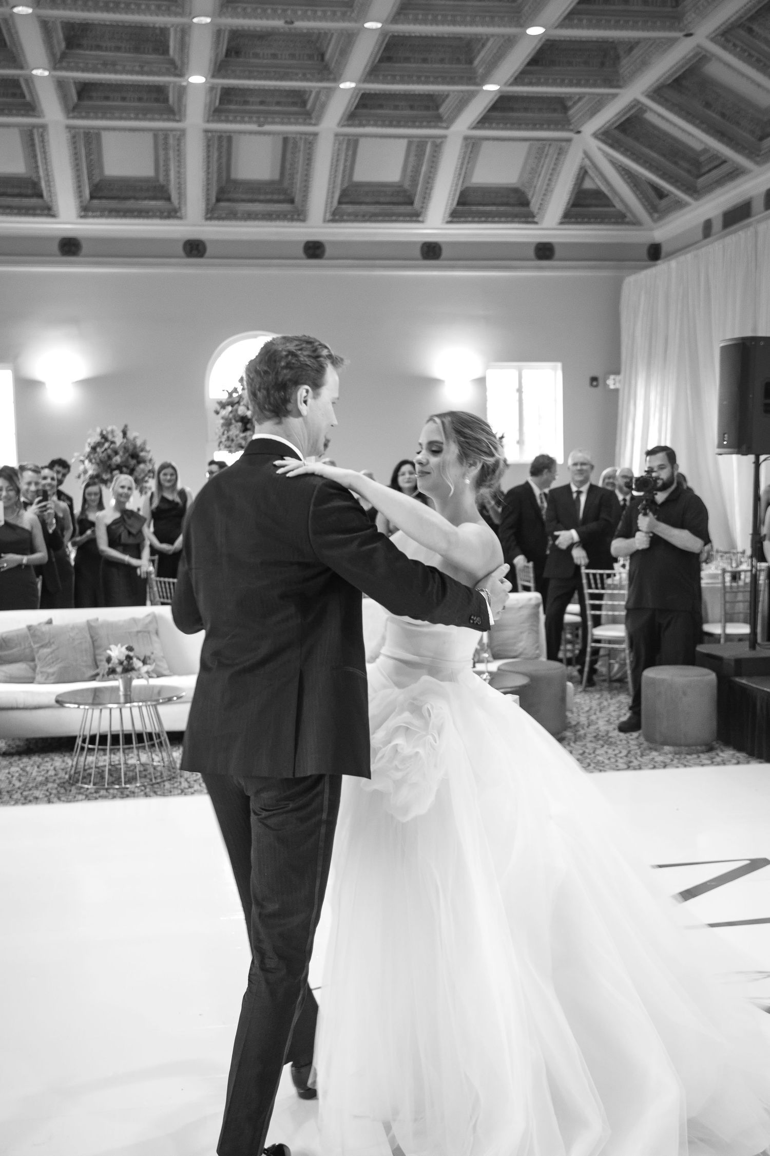 Black and white photo of bride and groom sharing their first dance at elegant wedding reception.