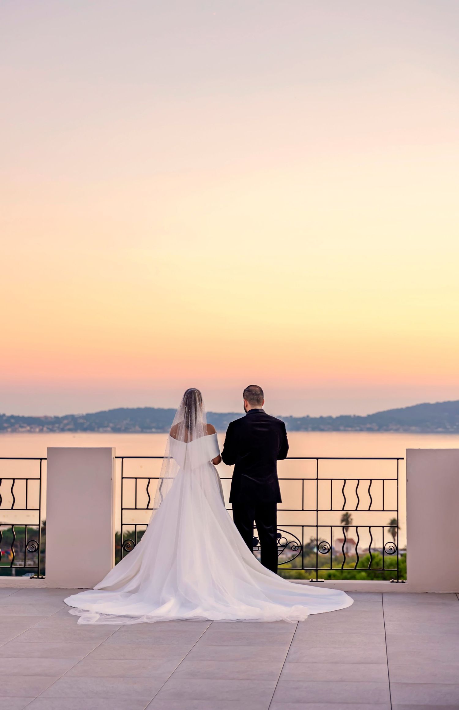 Romantic sunset wedding photos on a balcony overlooking mountains.