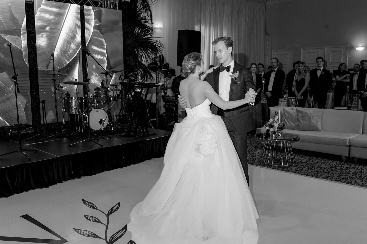 Black and white photo of a bride and groom sharing their first dance at an elegant wedding reception.