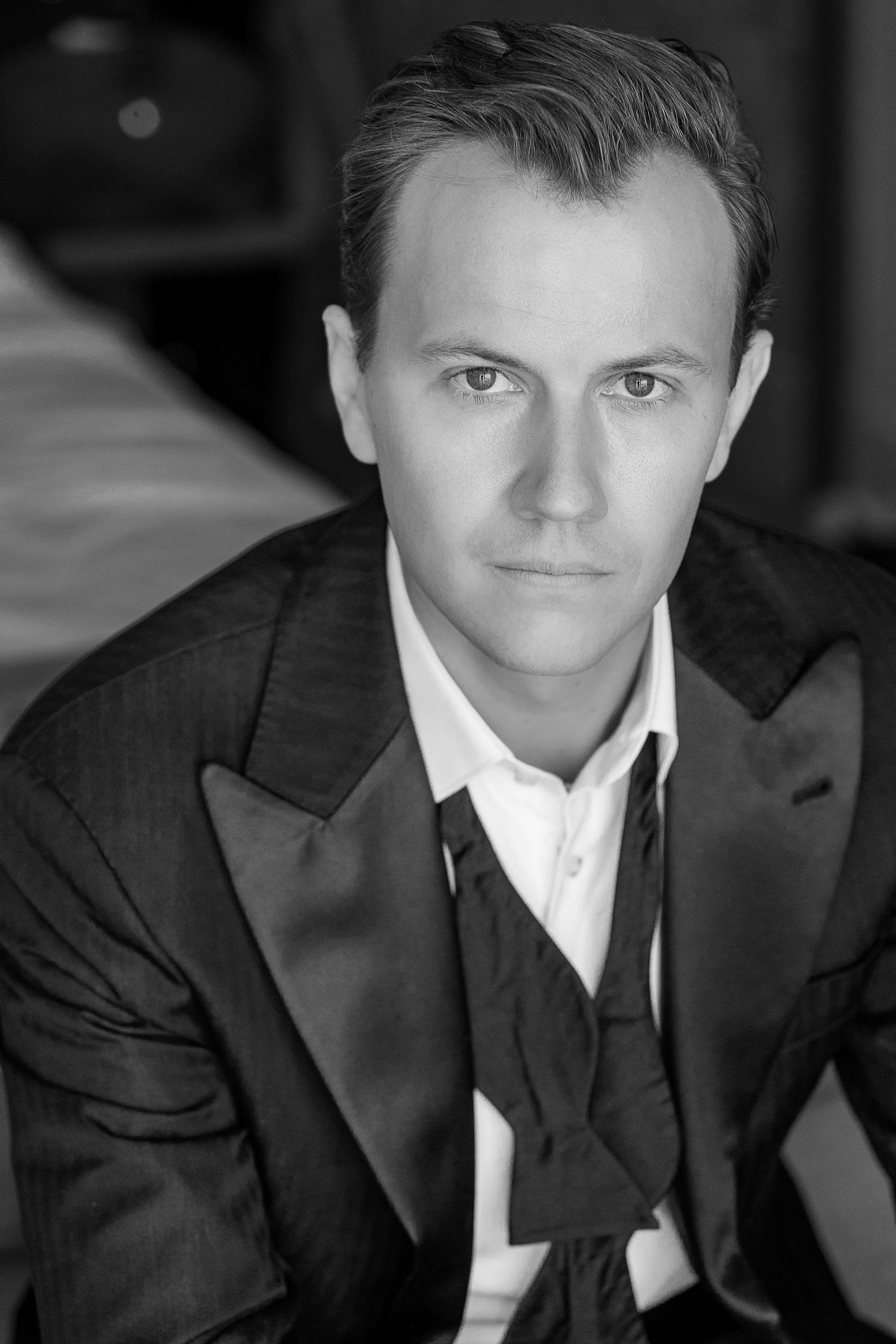 Black and white portrait of a well-dressed man in a formal suit with ascot tie, looking confidently at the camera.
