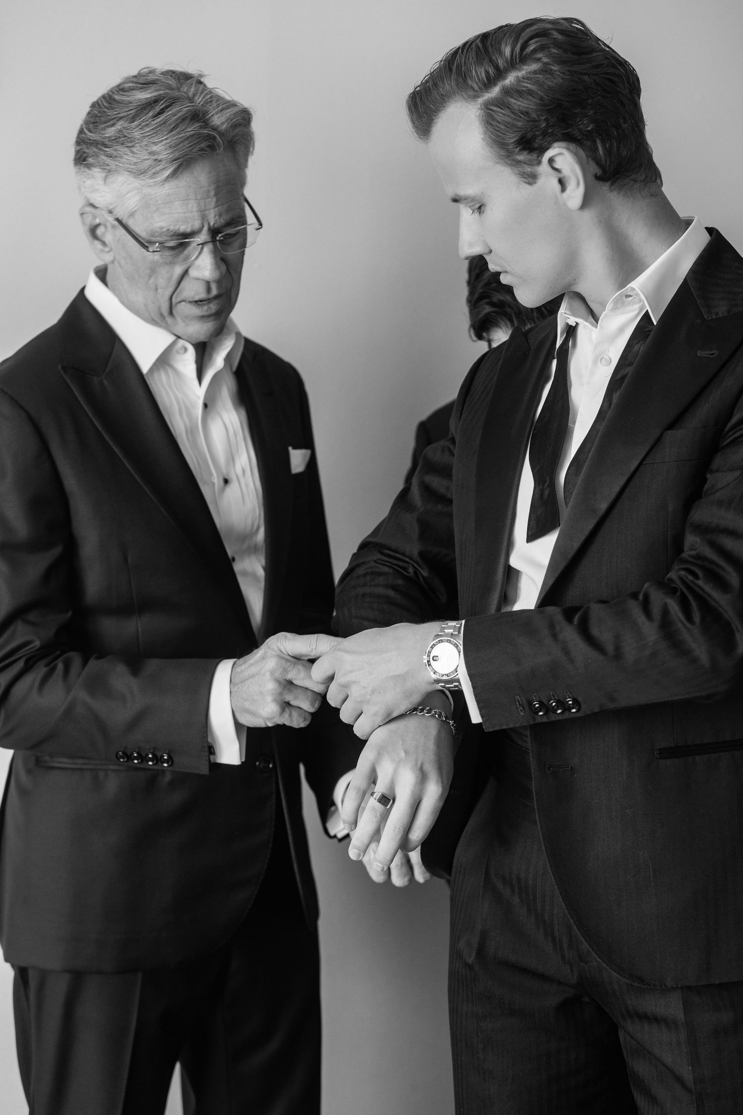 Two men in suits examining a luxury watch in a classic black and white portrait photo.