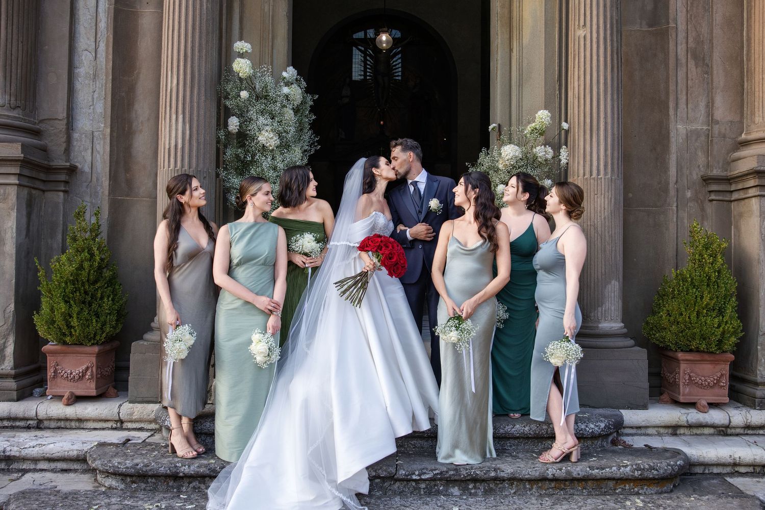 Wedding party poses in front of classic stone columns with elegant architecture.