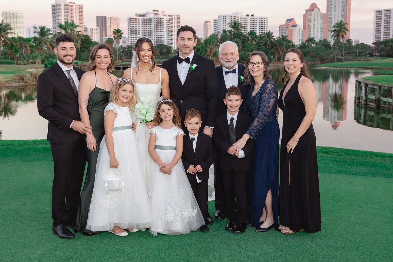 Family group photo at a formal wedding event outdoors, with adults and children dressed in elegant attire.