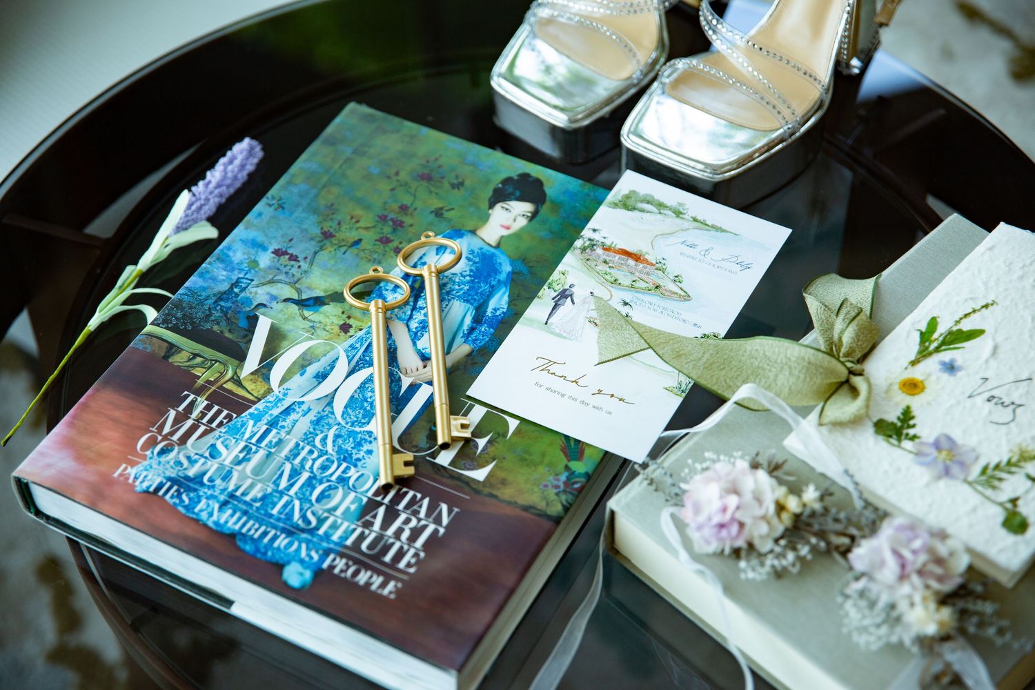 Wedding planning materials and accessories displayed on dark tray including books and floral details.