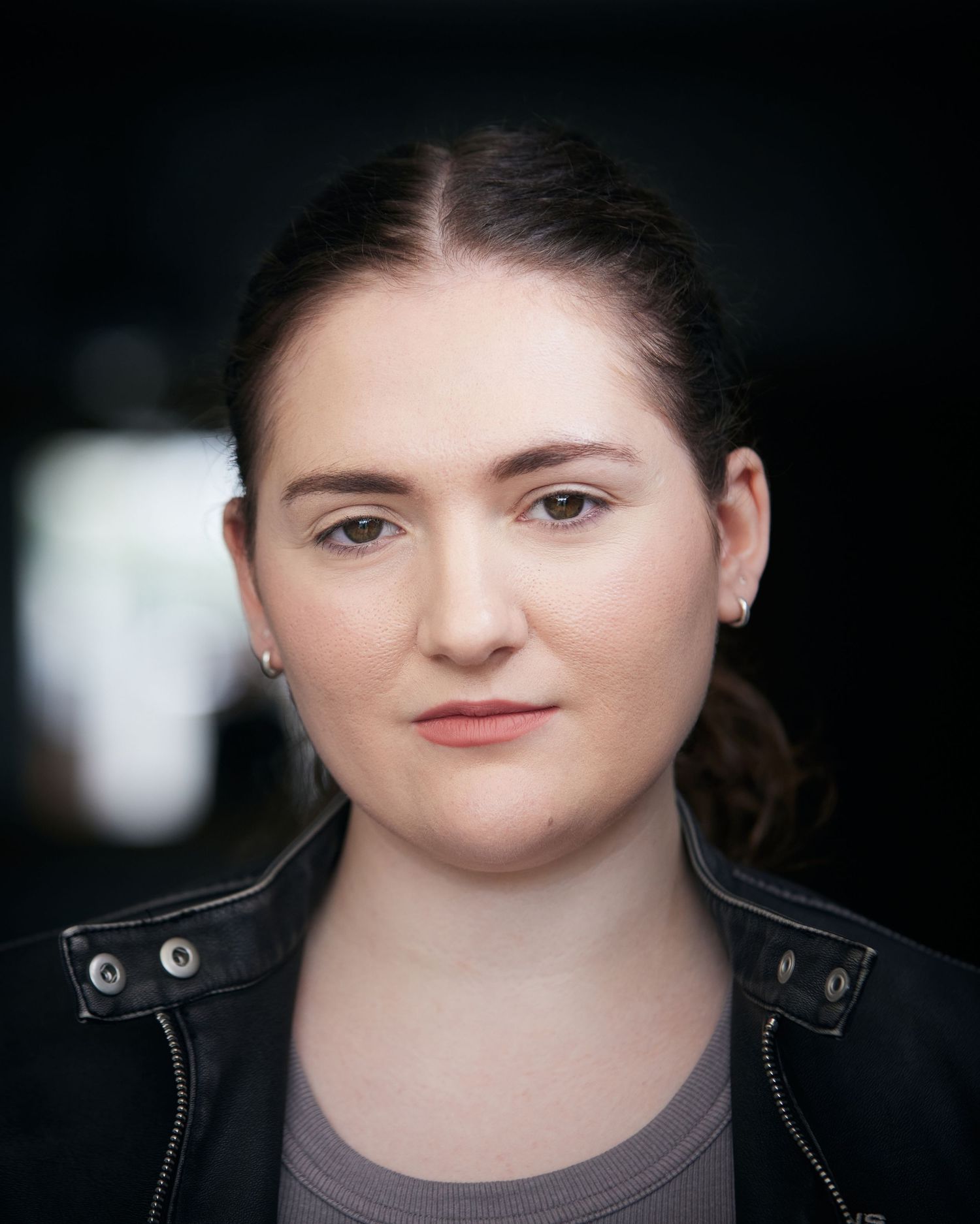 Rebel character headshot; sharp eyes with soft-focus Cardiff background.