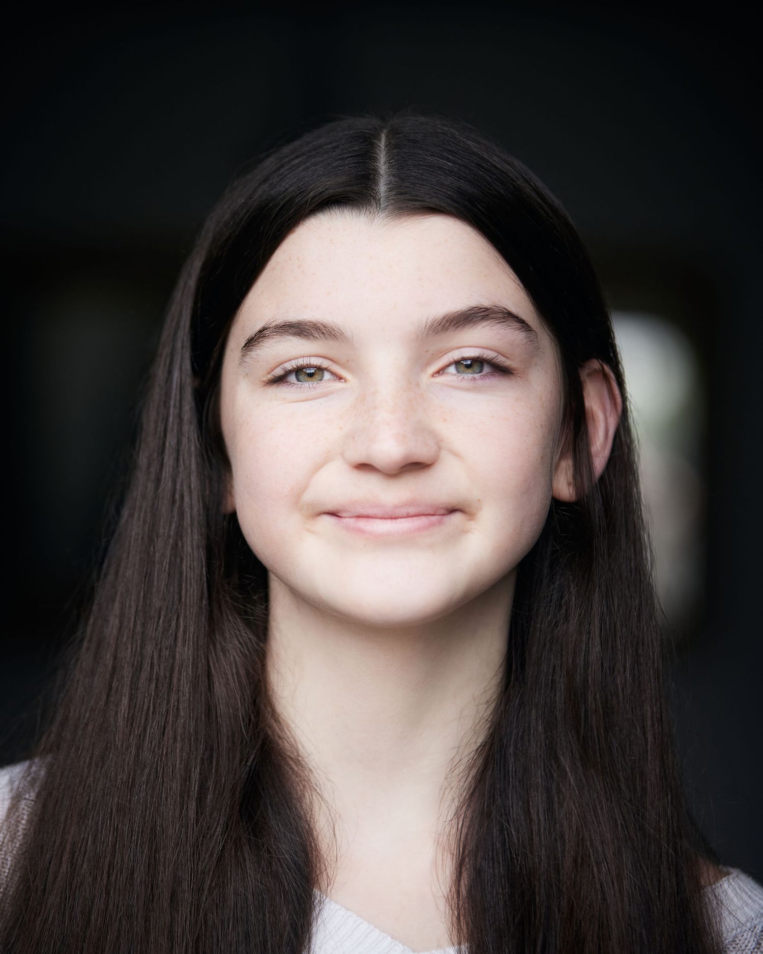 Friendly headshot; child performer with a natural, beaming smile in soft natural light.
