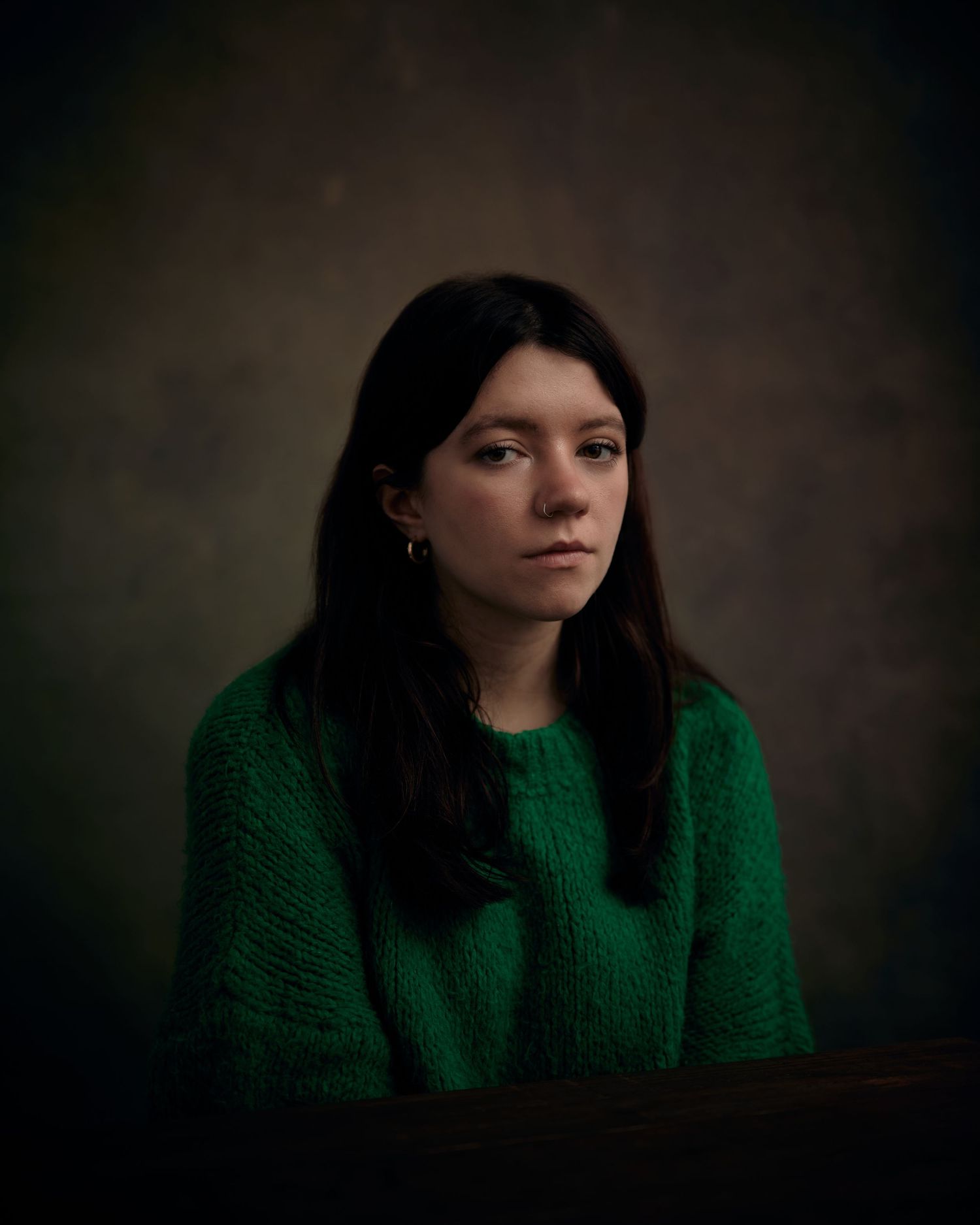 Strong character headshot; woman with a sharp, unwavering stare on a mocha background.