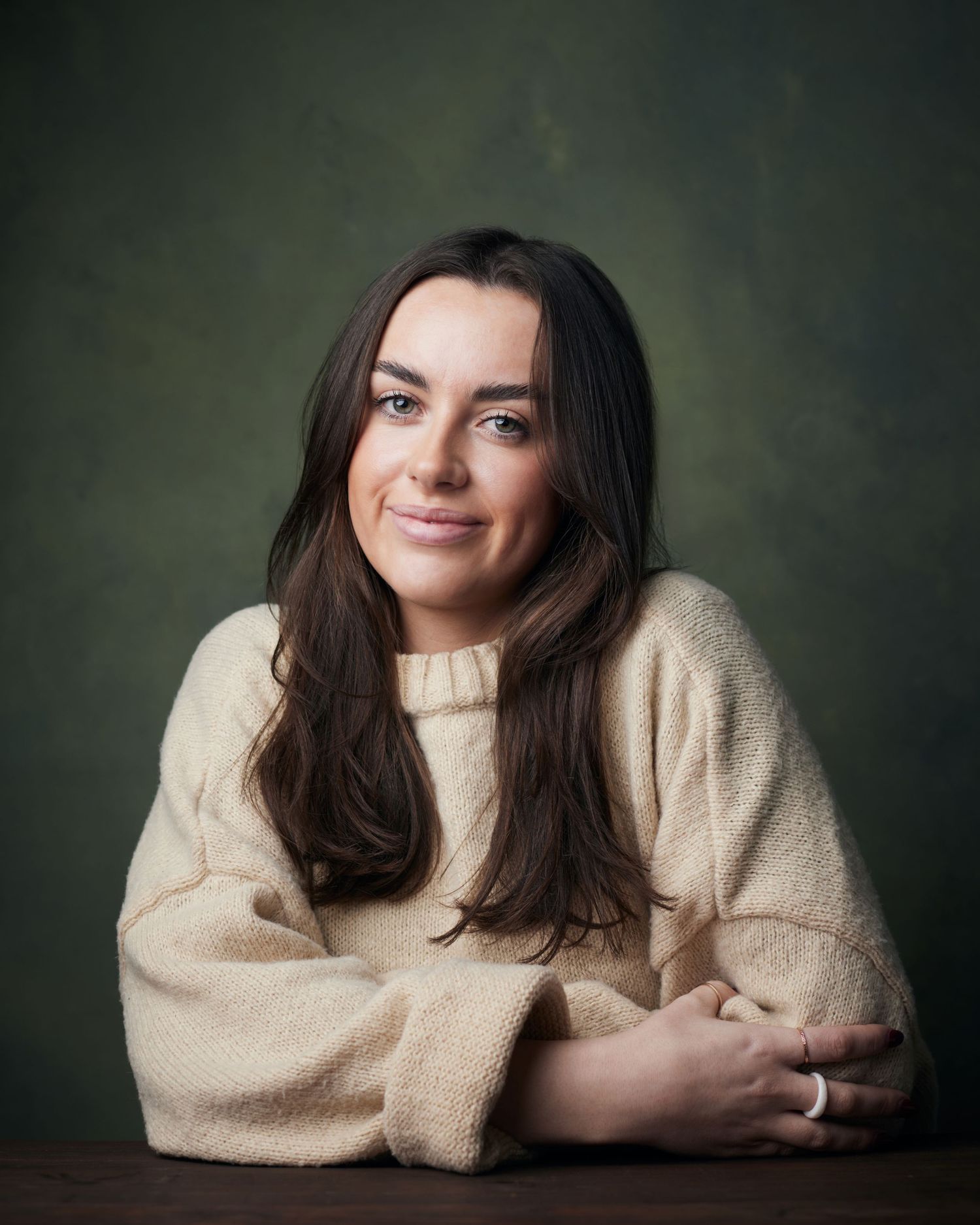 Warm studio headshot; actress in a crteam knit sweater with a gentle, approachable gaze.