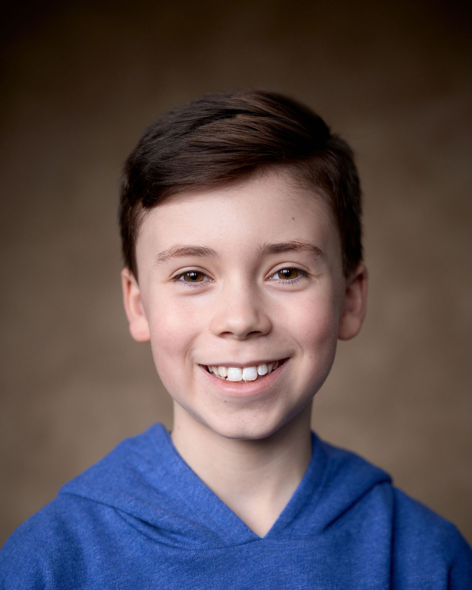 Smiling child actor Dylan in a blue hoodie. Bright, commercial-style headshot for Spotlight, taken by Cardiff’s Geraint Todd.