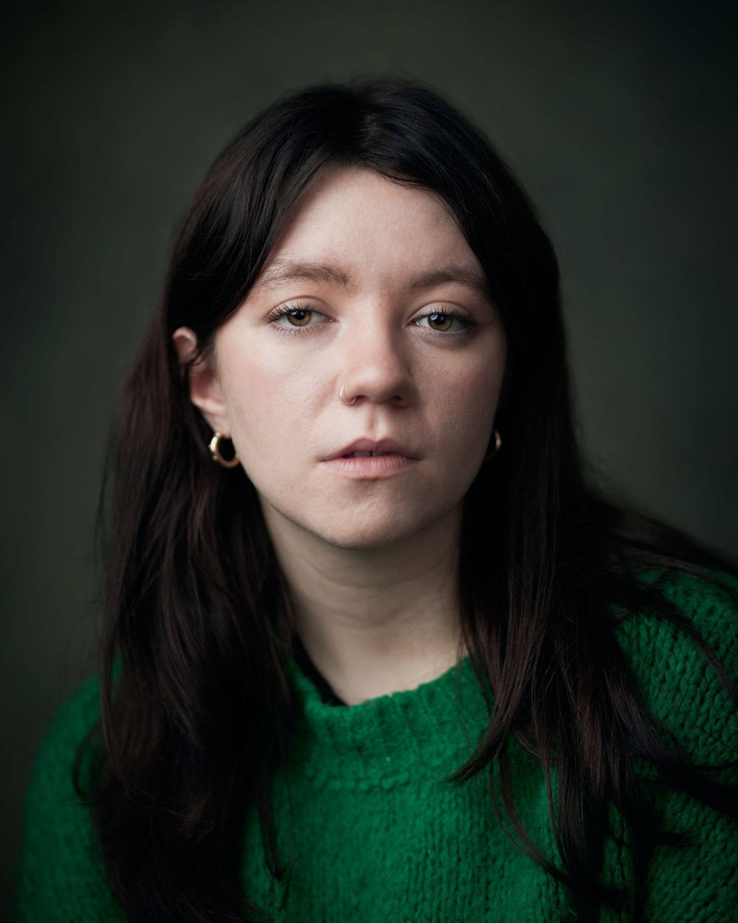 Sharp studio portrait; female actor with a strong, defiant facial expression against green.
