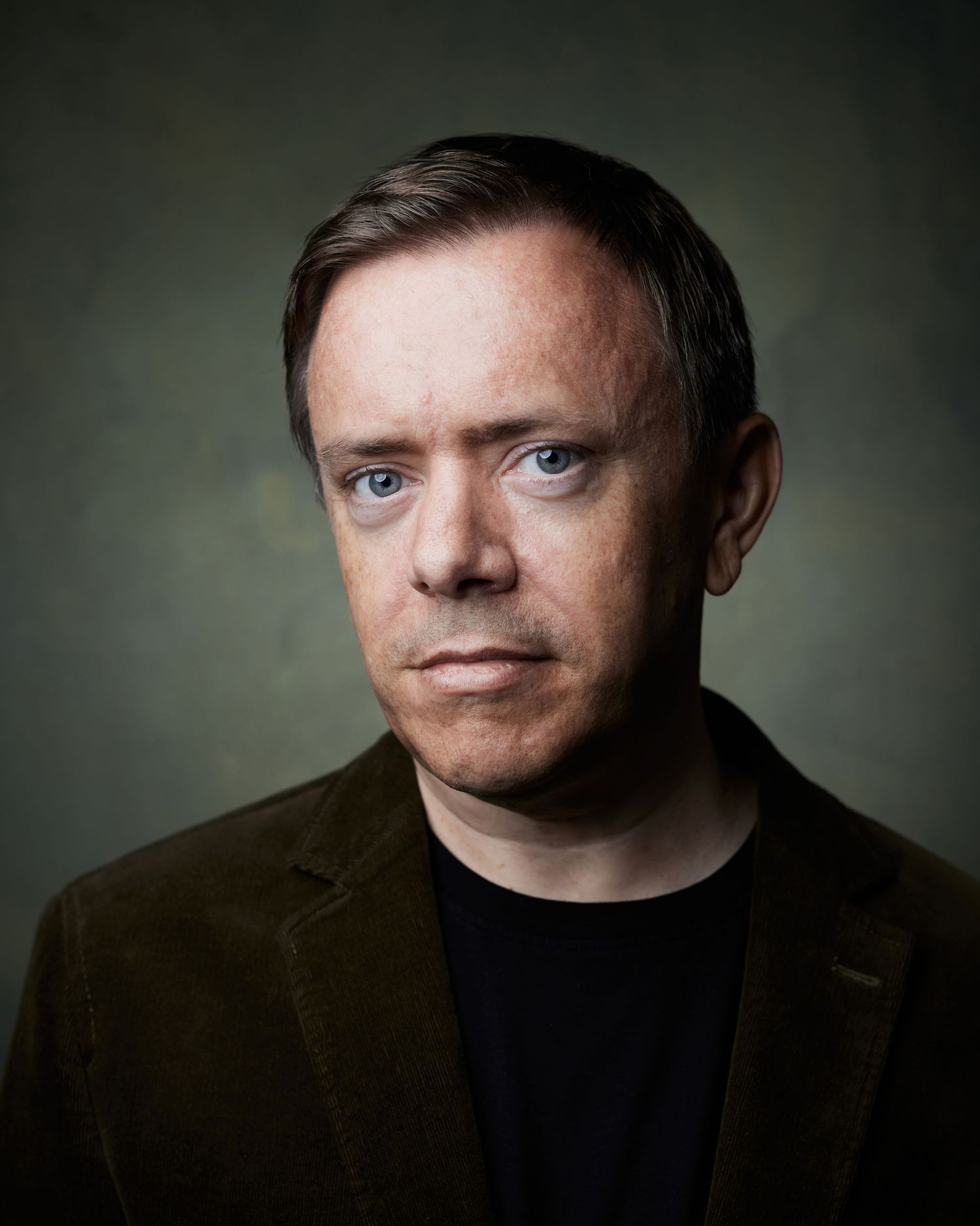 Resolute headshot; man with a stoic and powerful facial expression in-studio.