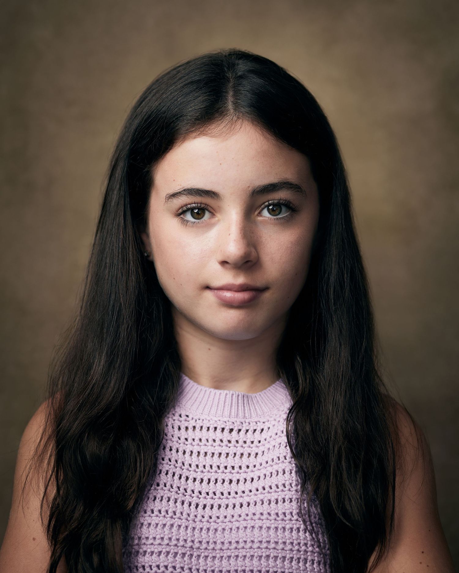 Elegant headshot; young actress with a calm, centered presence on a brown backdrop.