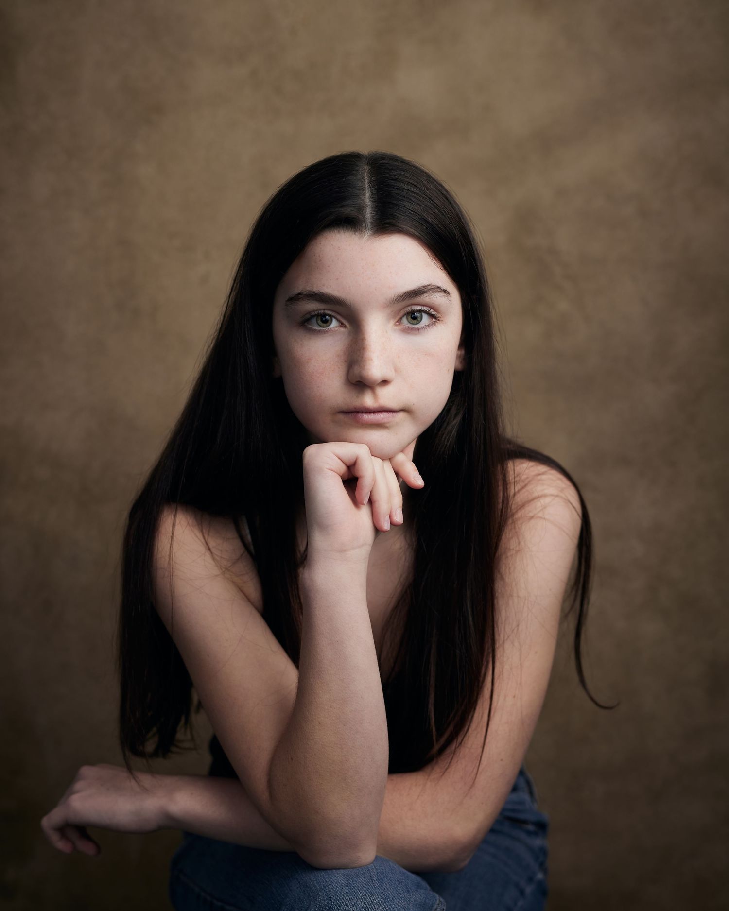 Intense studio portrait; female actor with a serious, commanding presence against brown.