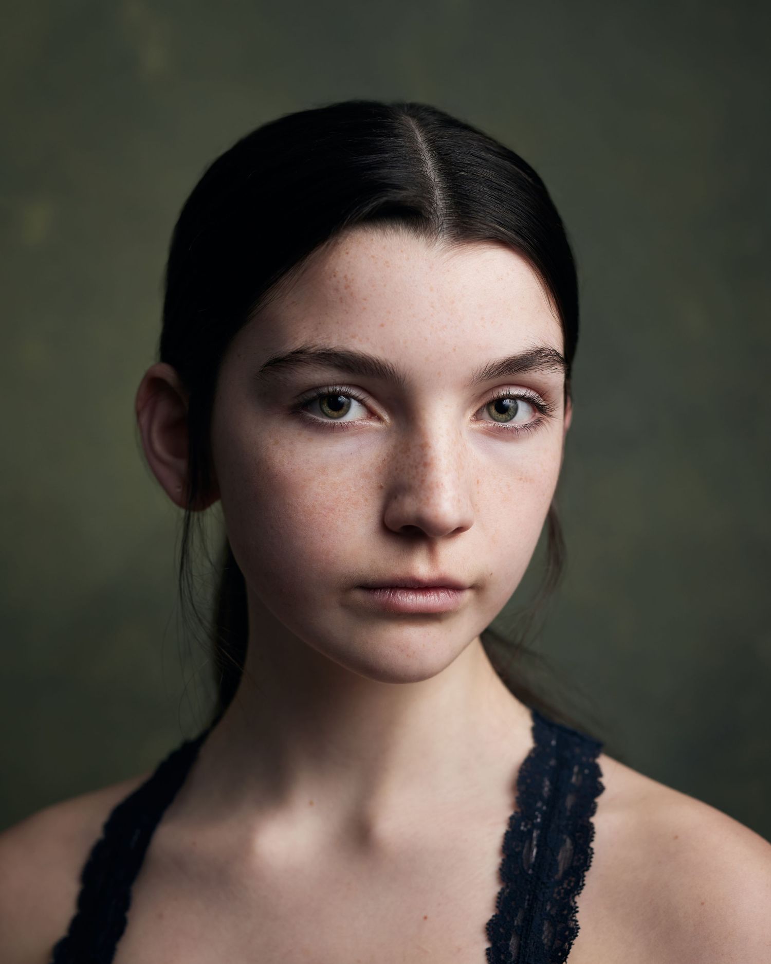 Period drama headshot; child actress with classic styling and a poised expression on green.