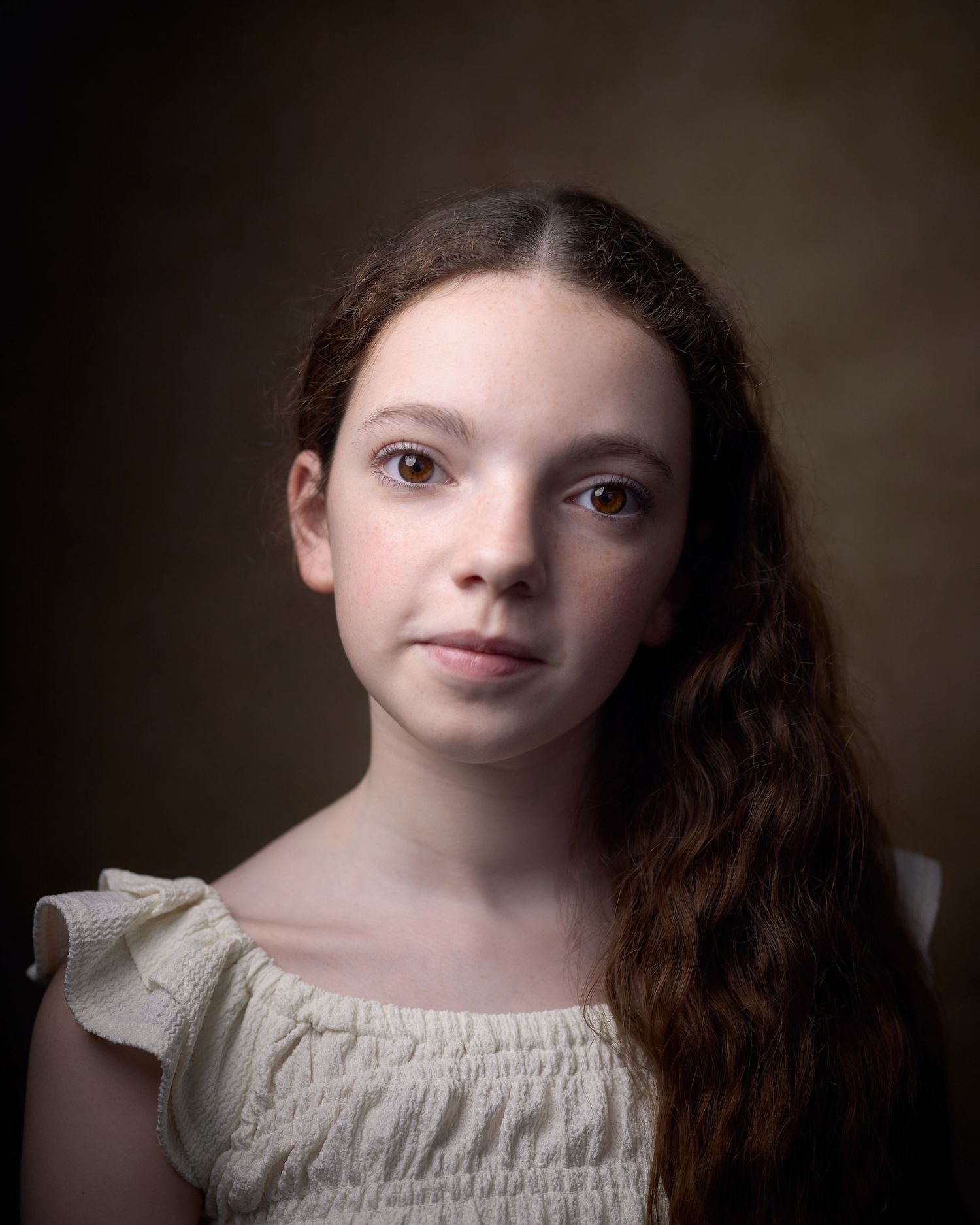 Warm, commercial headshot of child actor Ophelia. Natural, approachable expression with soft lighting on a warm ochre background in Cardiff.