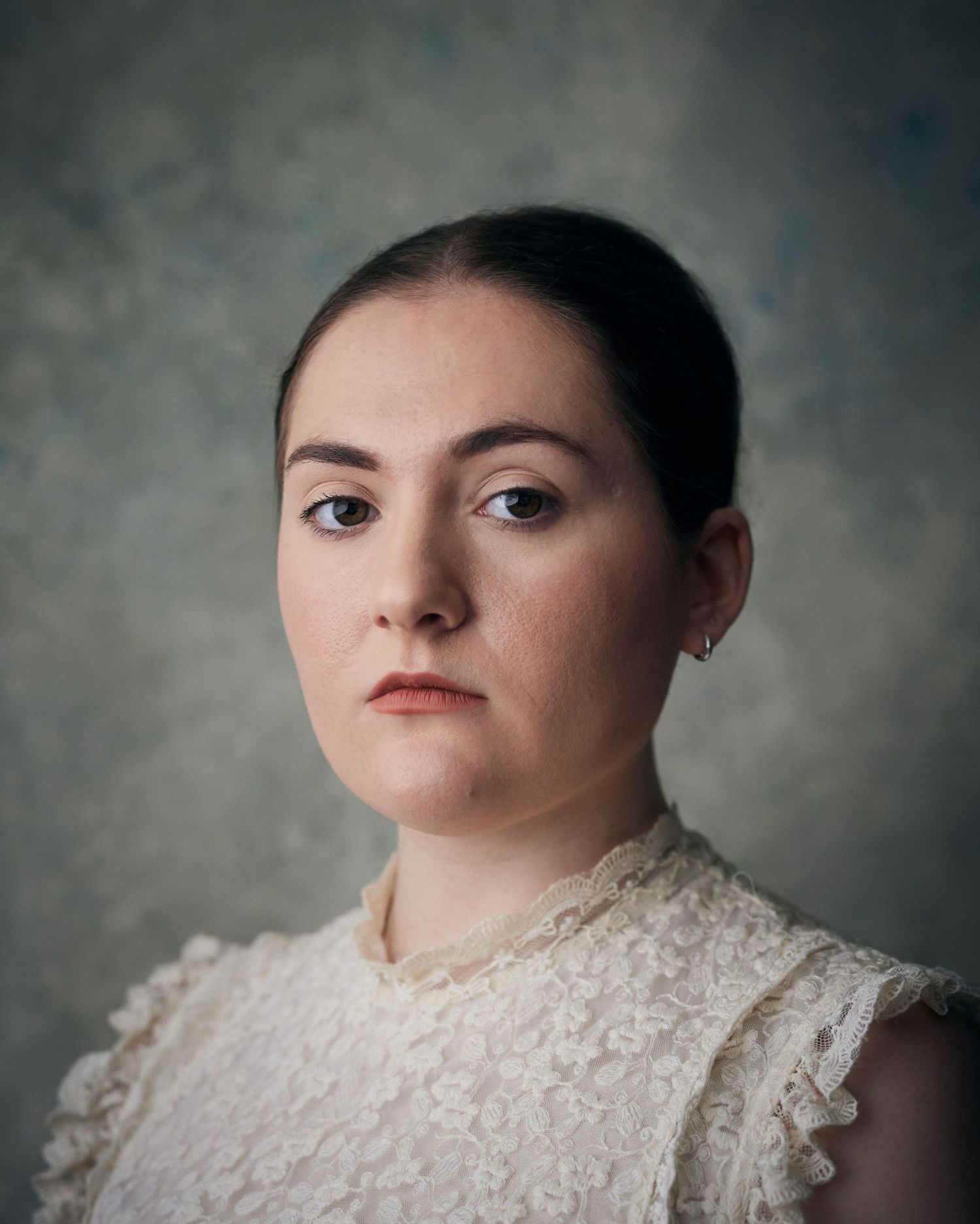 Timeless headshot; woman with a stoic, classical look and painterly studio light.