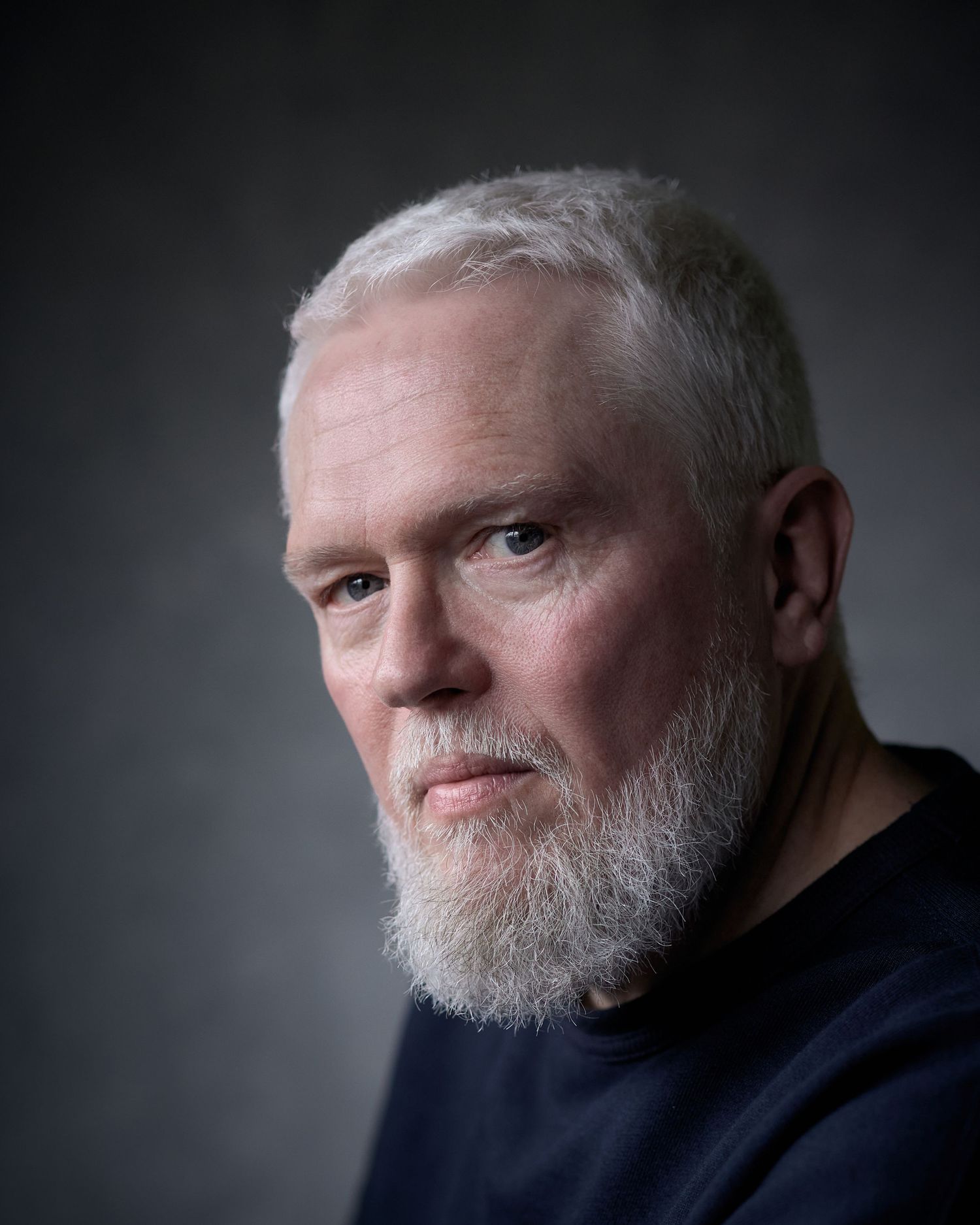 Dramatic headshot of actor Jeremi Cockram featuring soft side-lighting and a textured grey backdrop.