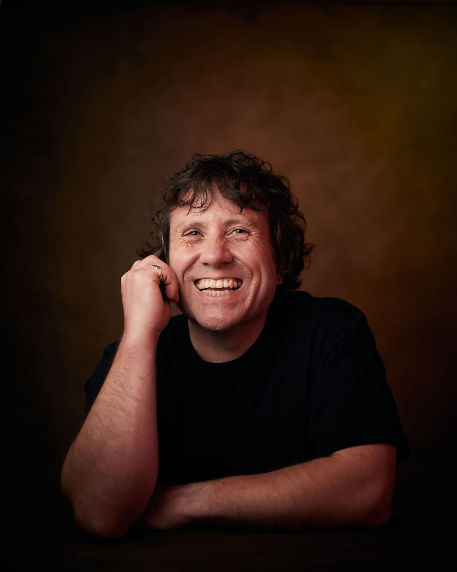 Smiley actor headshot; man with a natural, beaming grin and laughing eyes.