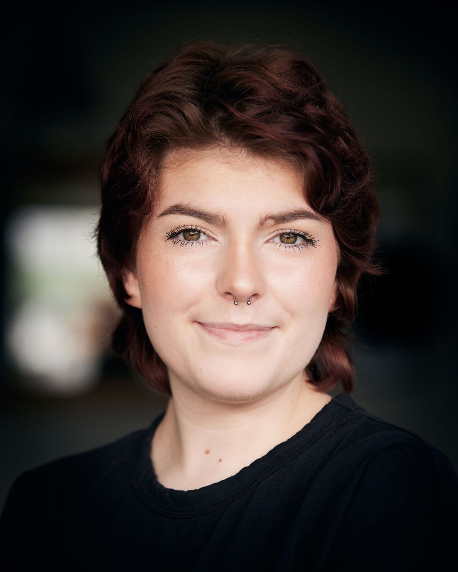 Friendly character headshot; bright eyes with soft-focus Cardiff natural background.