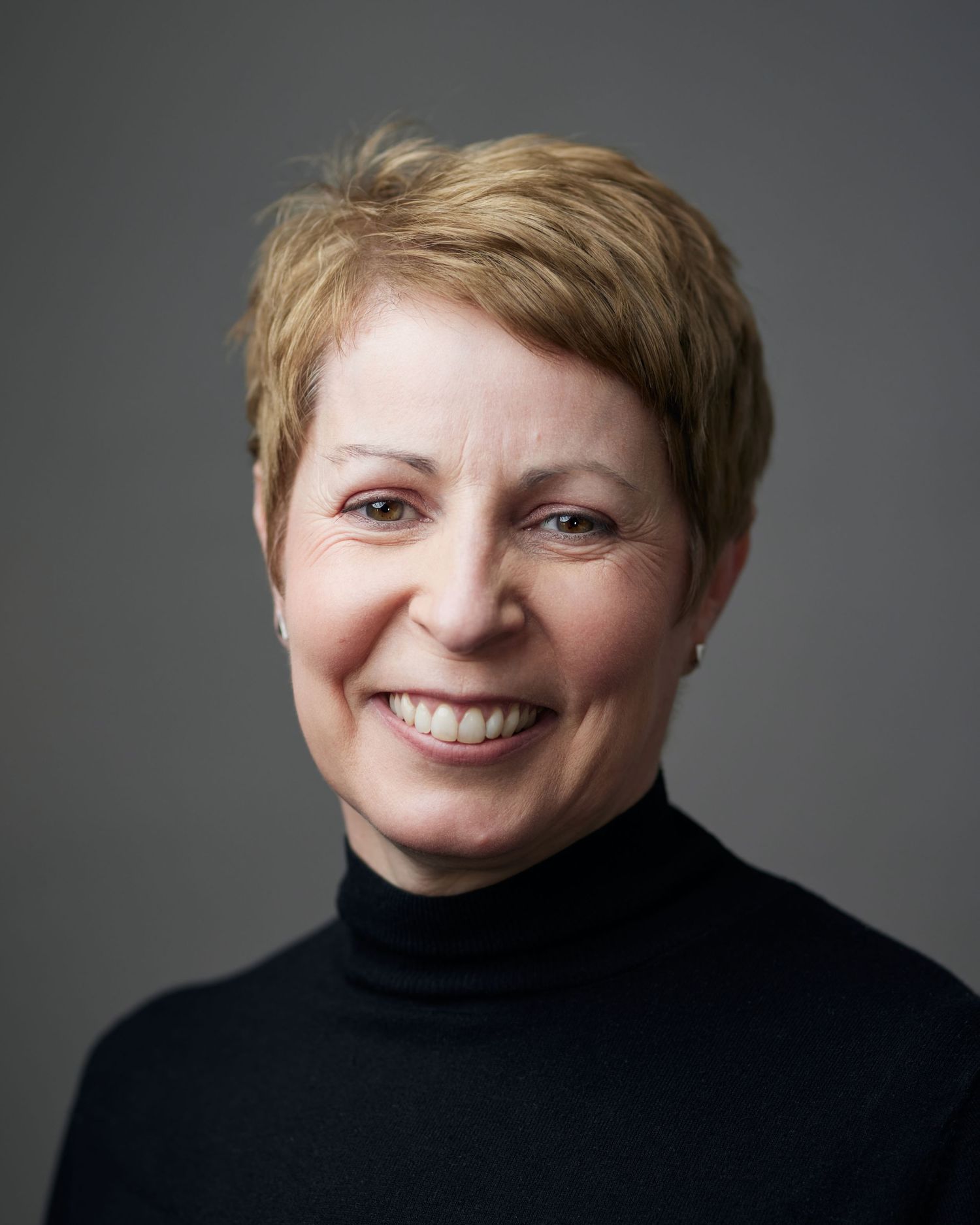 High-end executive headshot of a female professional on a grey background.