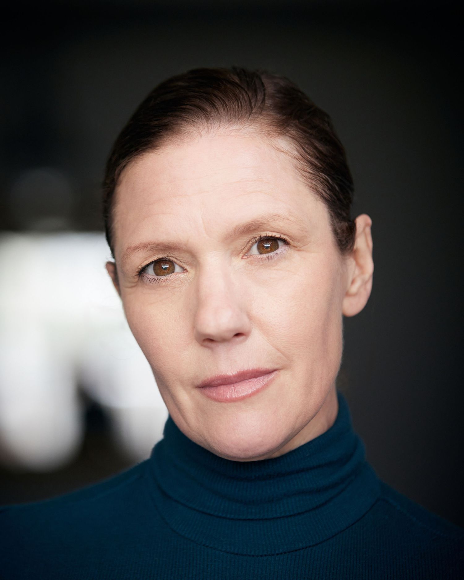 Authoritative headshot; stern gaze with soft-focus Cardiff background.