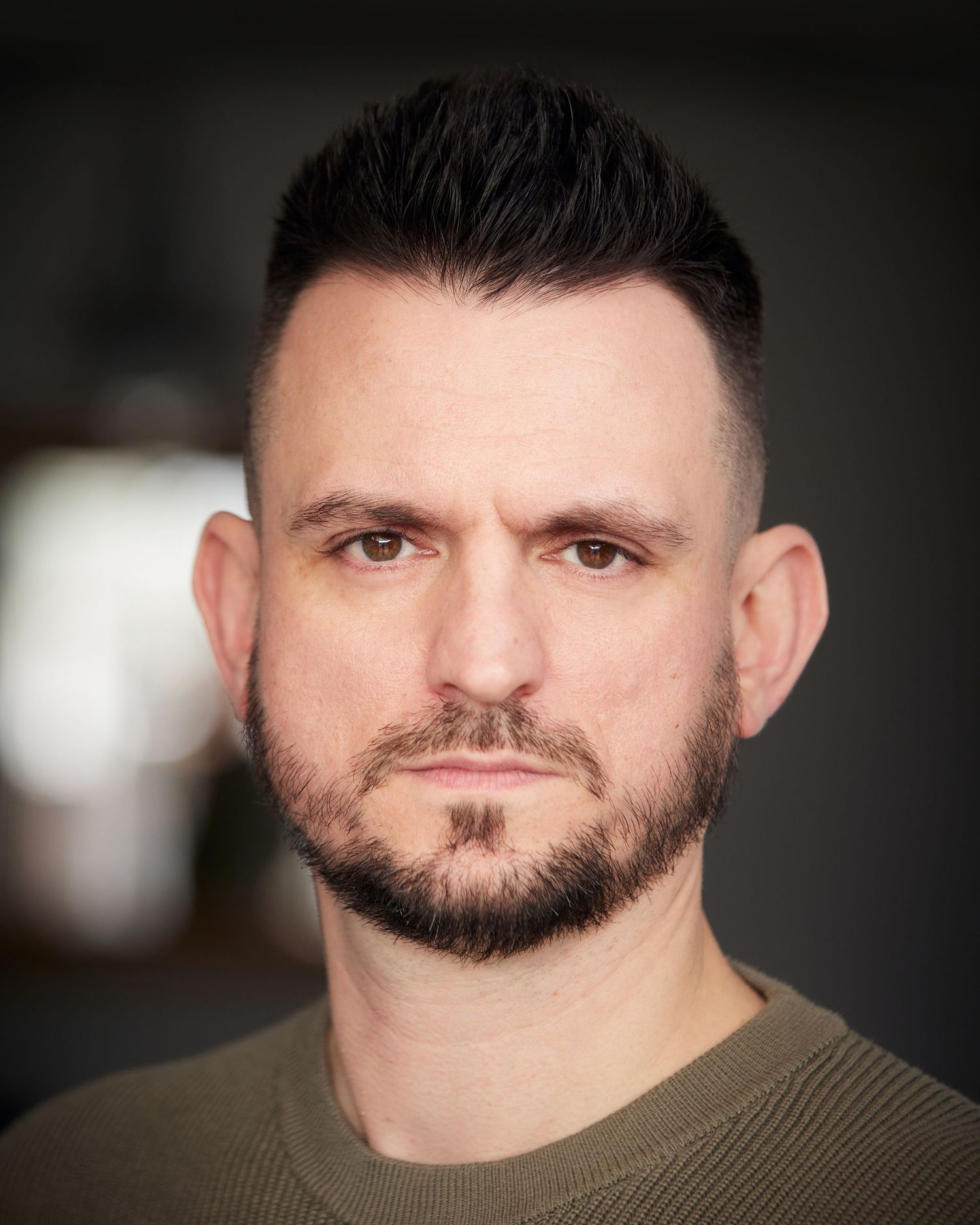 Edgy character portrait; defiant gaze with soft-lit background.