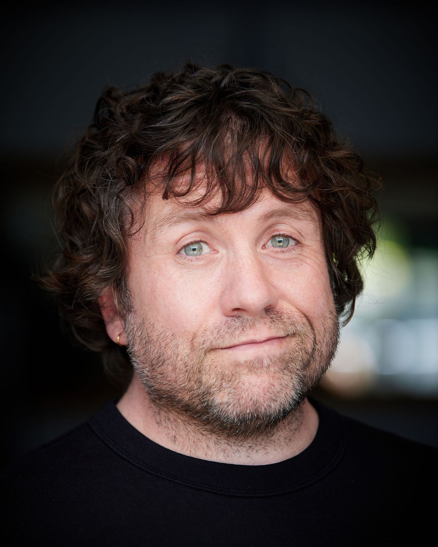 Upbeat actor headshot; comedic presence in Cardiff daylight.