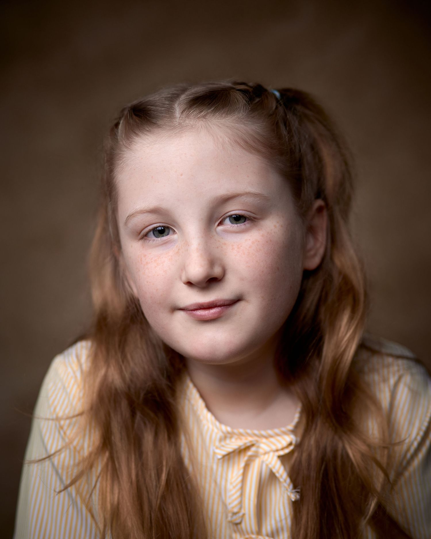 Natural, modern child actor headshot. Warm earth tones, soft lighting, and a subtle expression. Ideal for contemporary TV drama casting.