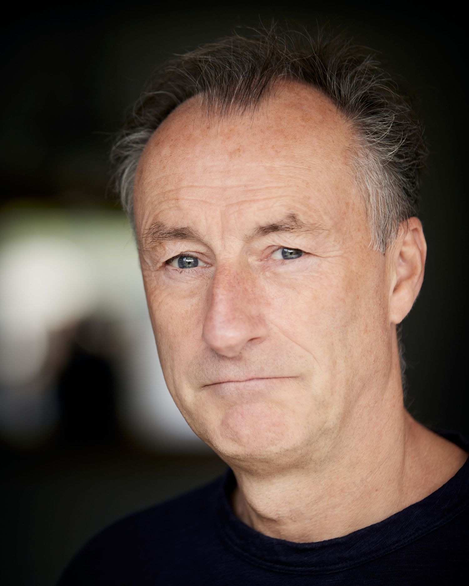 Welcoming character portrait; approachable presence with blurred Cardiff bokeh.