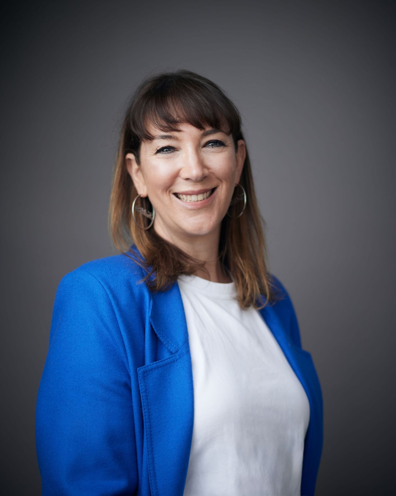 Radiant business portrait; woman with a wide, friendly smile for a Cardiff professional setting.
