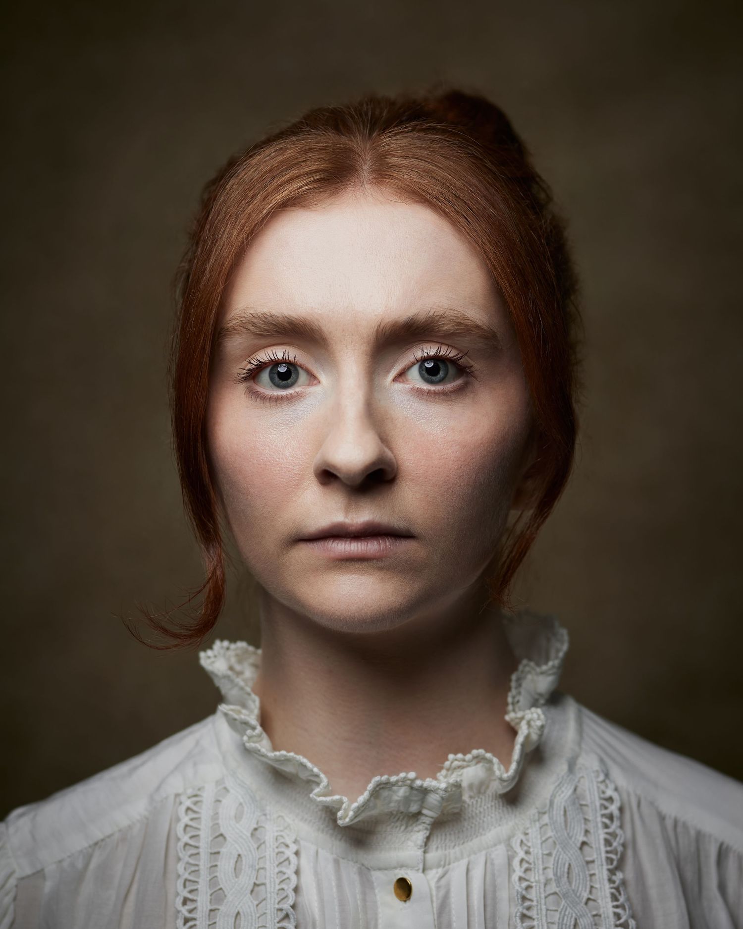 Formal studio portrait; woman with a Victorian-inspired aesthetic on a brown backdrop.