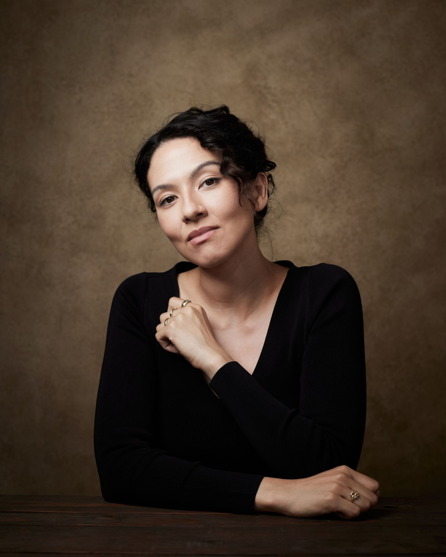 Elegant headshot; actress with a calm, centered presence on a brown backdrop.