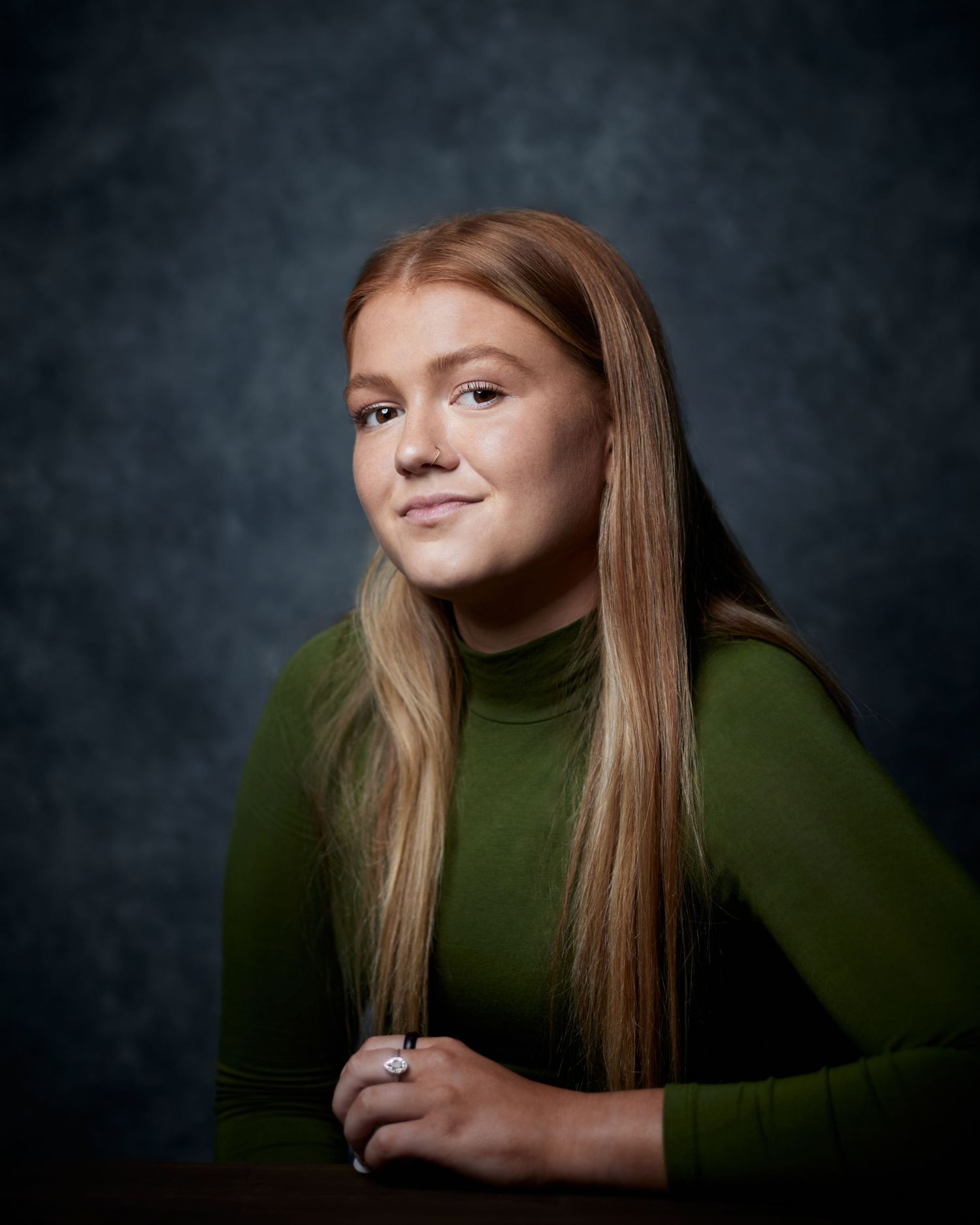 Radiant smiley portrait; actress with a lighthearted energy in a studio with a blue canvas backdrop.